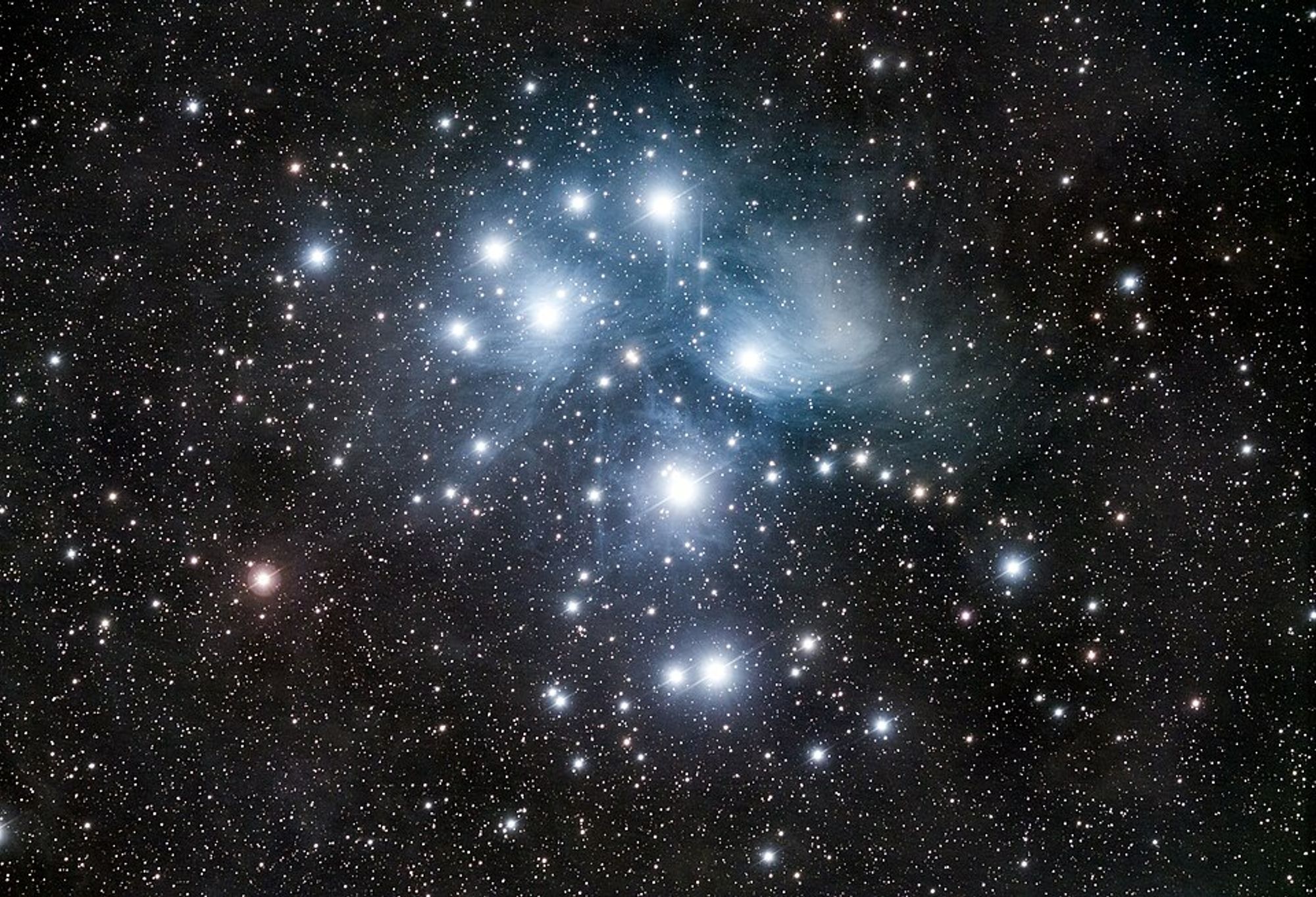 Shiny blue orbs at the center of a scatter of stars against the black sky.