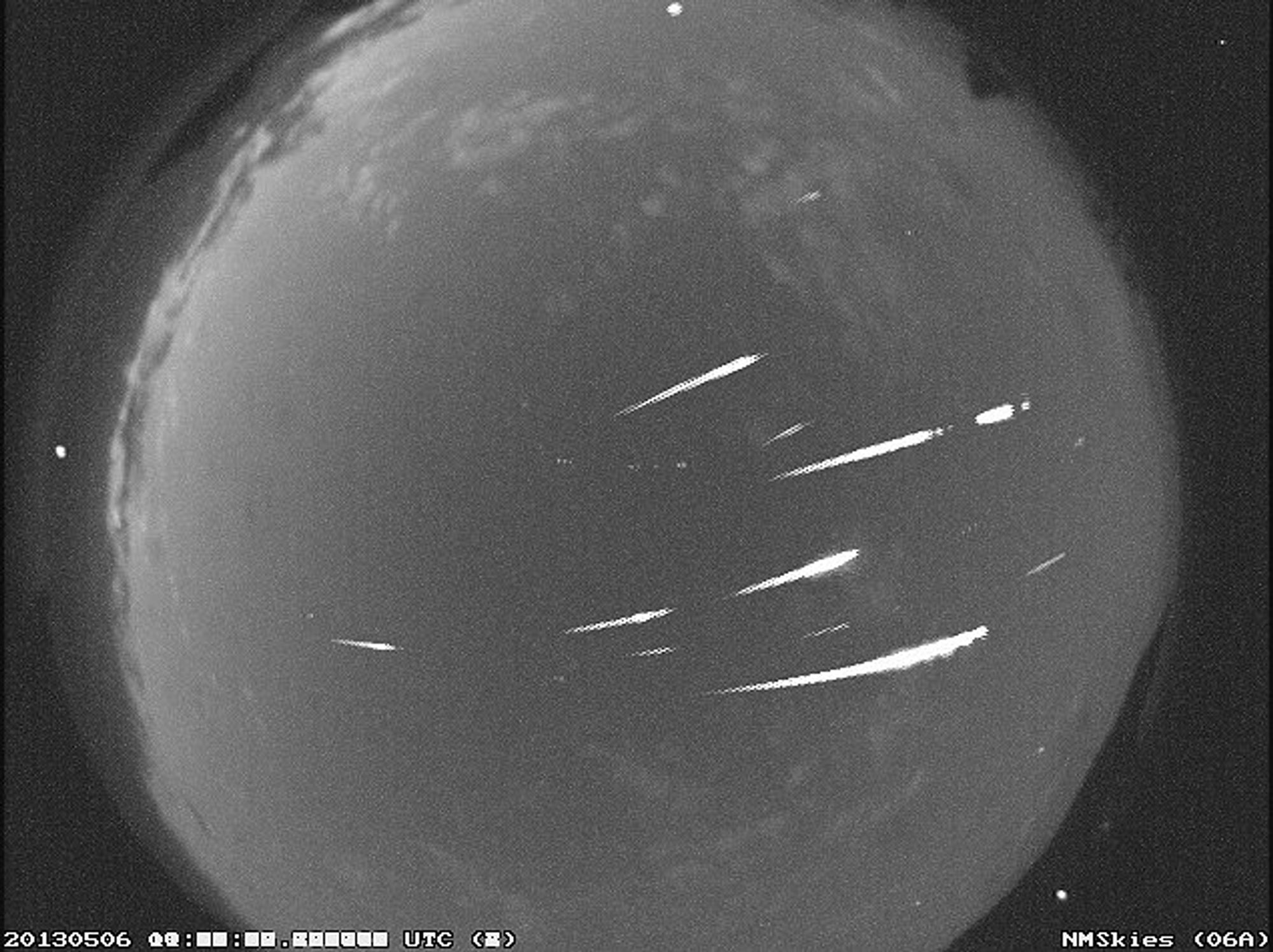 A grey image of meteors streaking across the sky