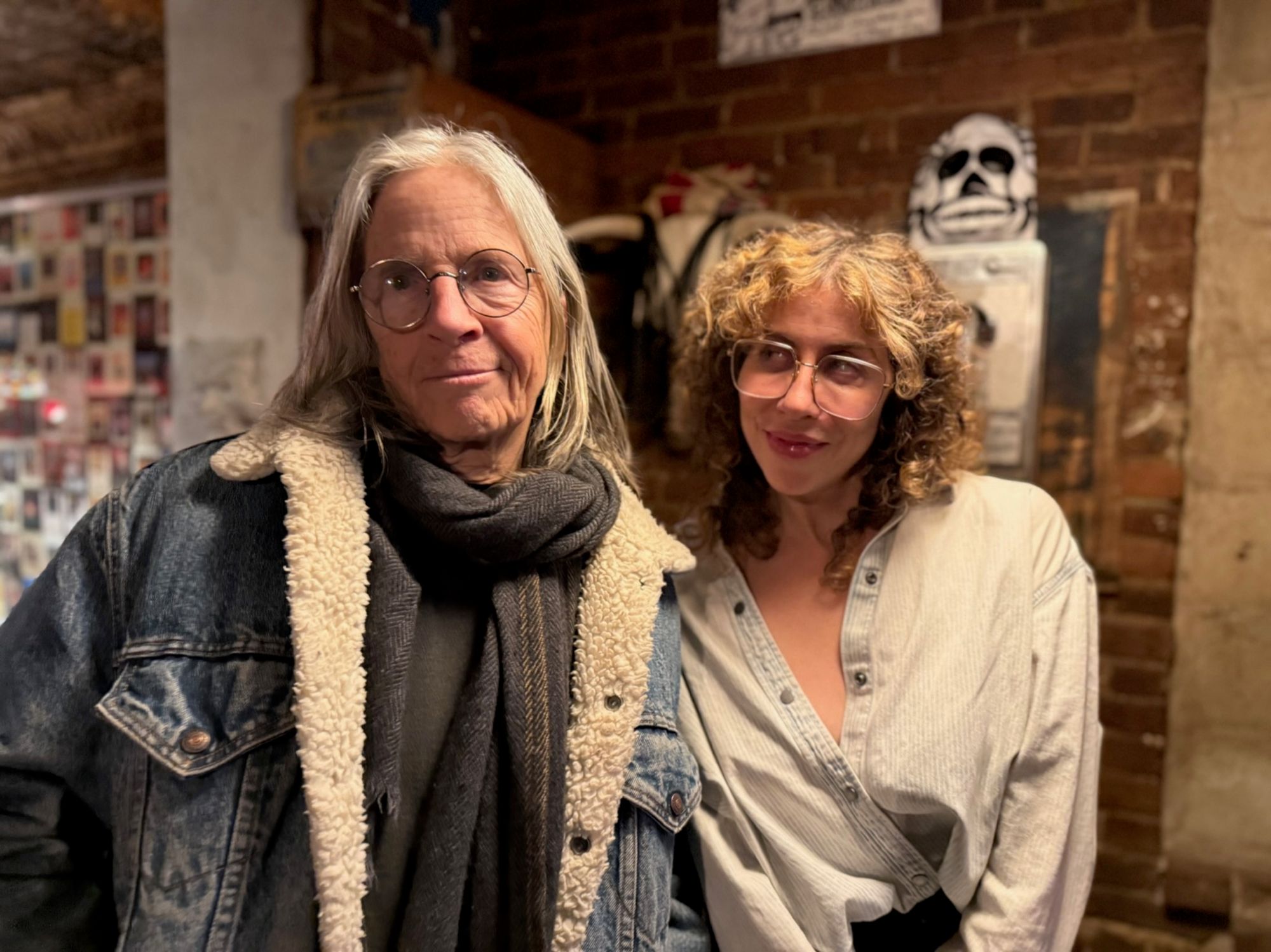 Eileen Myles and Ariana Reines pose together against a brick wall.
