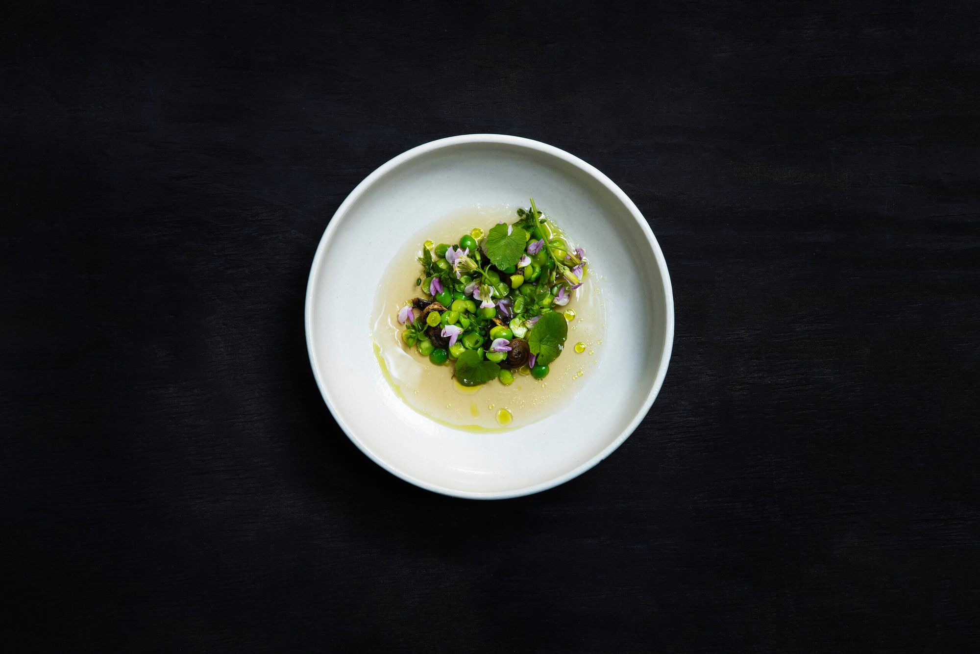 A plate of peas and razor clams on a black background
