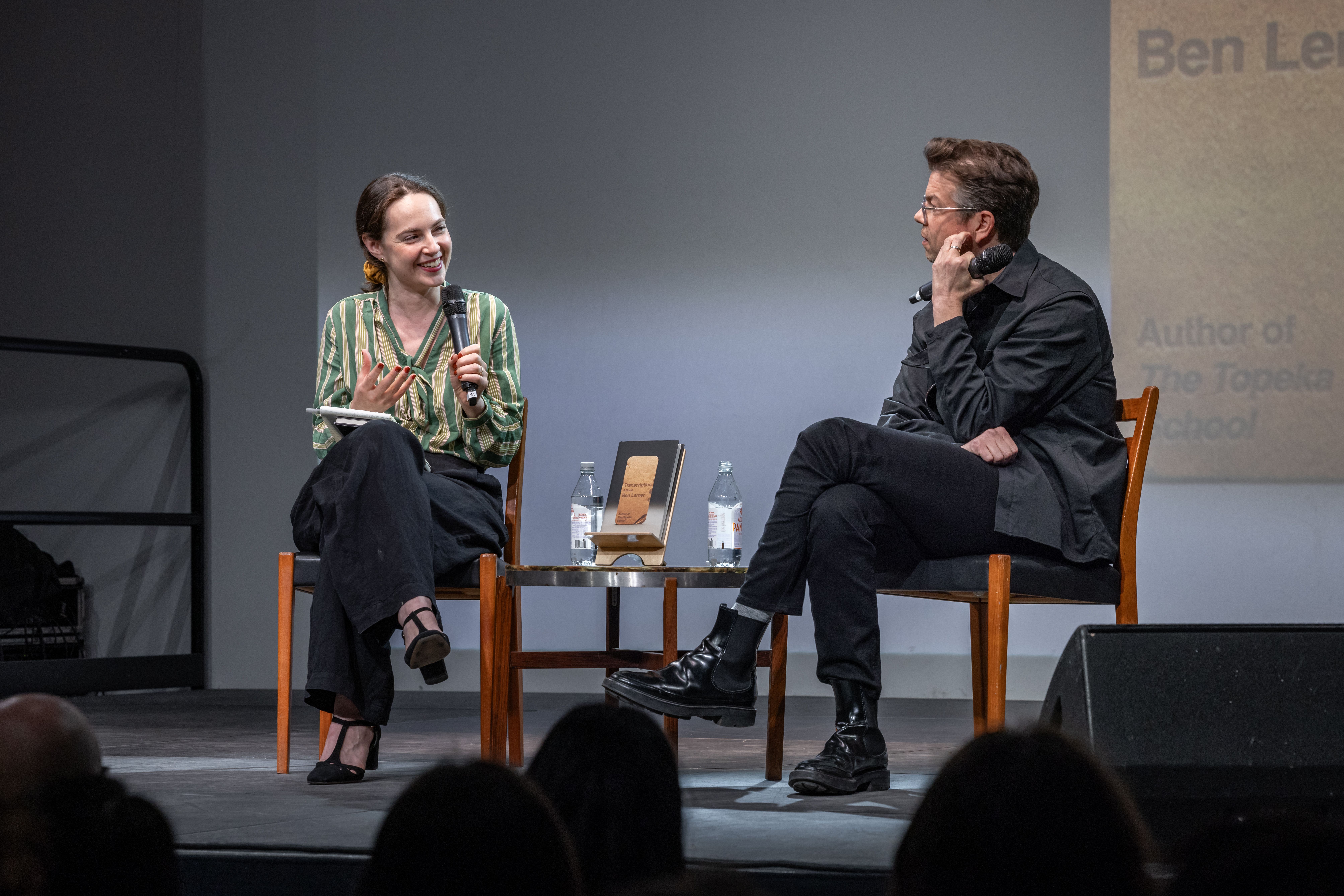 Alexandra Schwartz and Ben Lerner smile and speak into microphones, spotlit on stage.