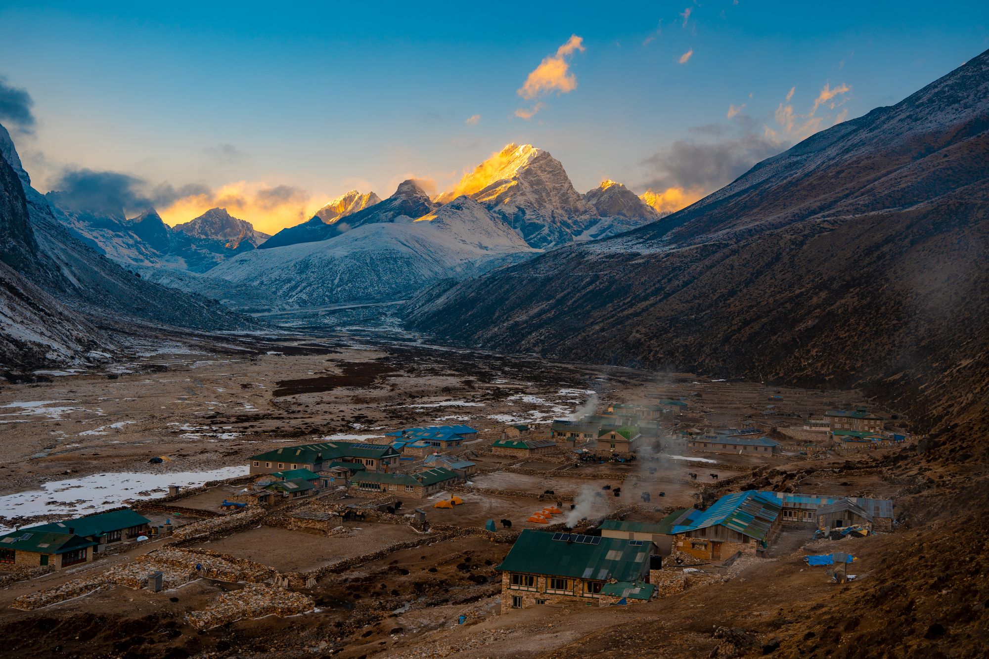 A beautiful sunset in the mountains of Nepal, featuring a small village in the foreground.