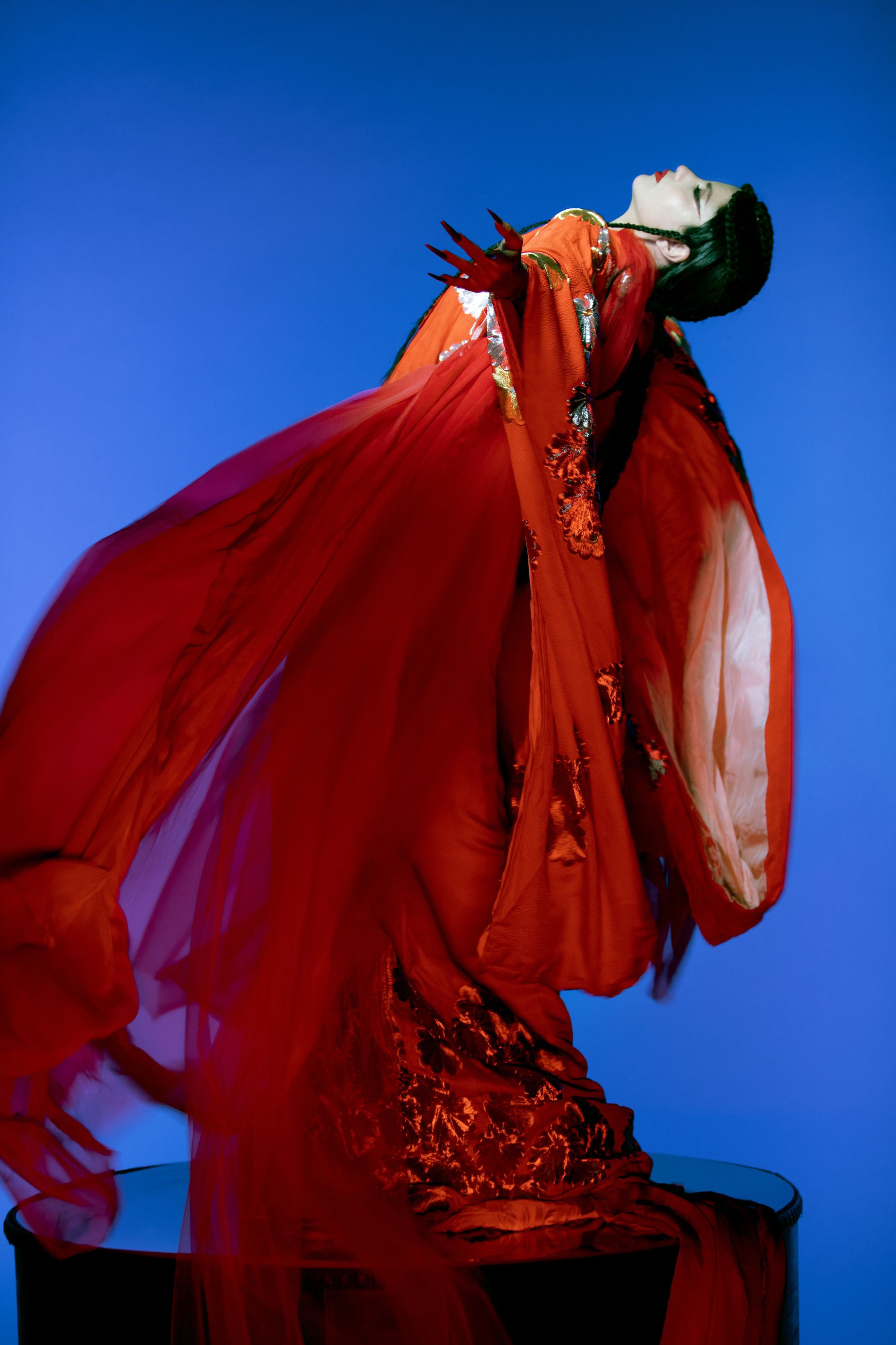 picture of emel with a black cape on and red background