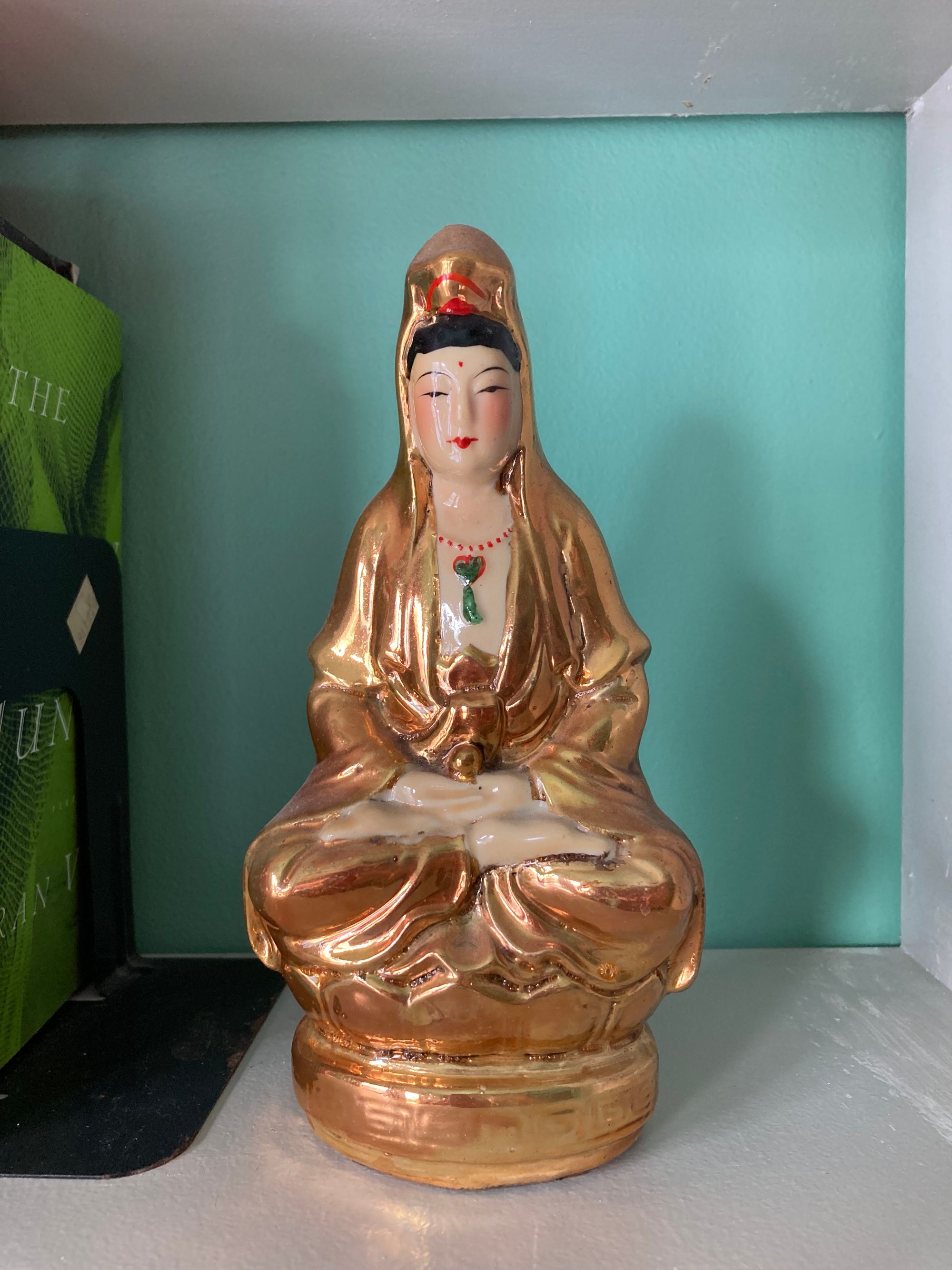 A small, colorful figurine of a the Guan Yin