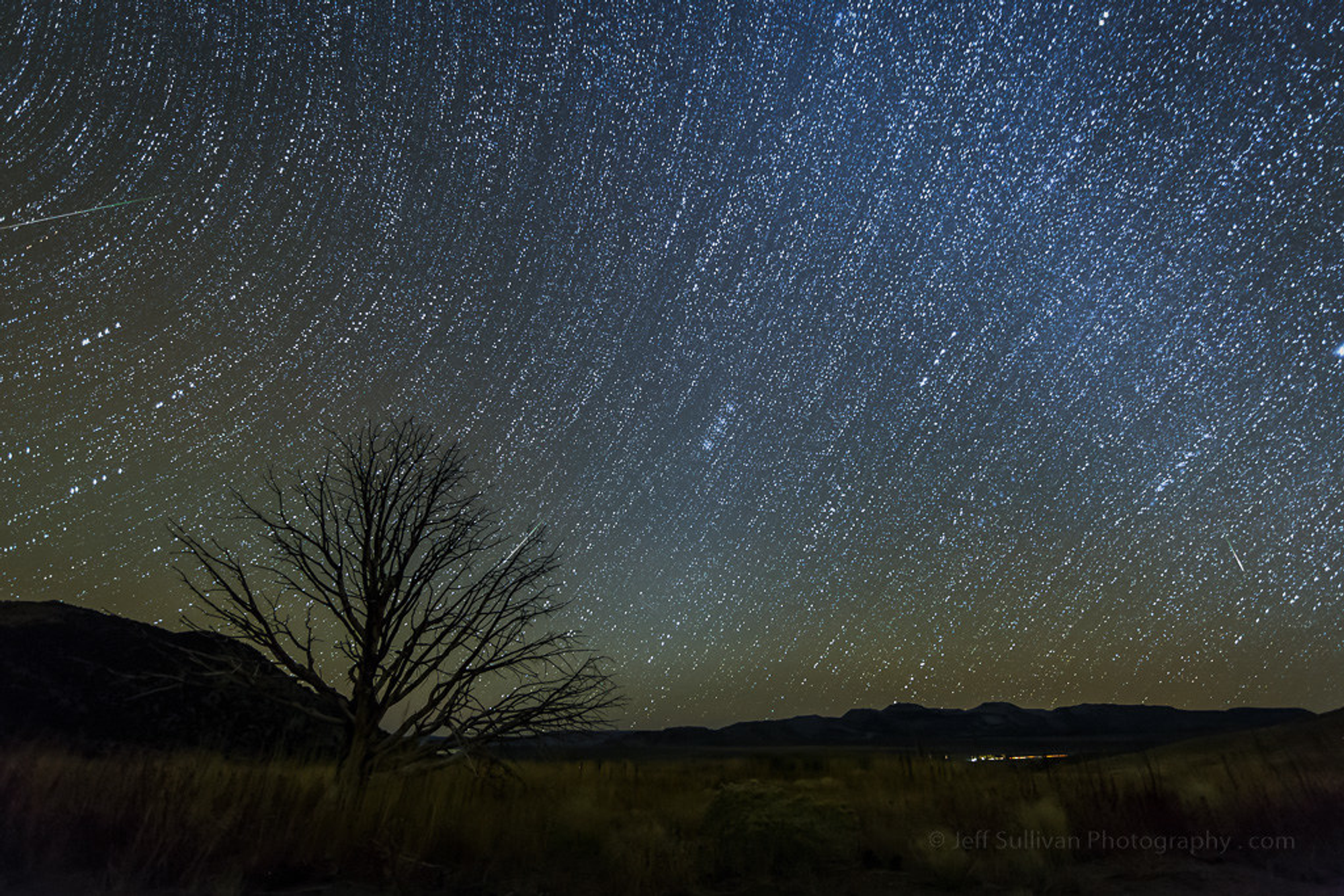Meteors showering across a black blue and green sky