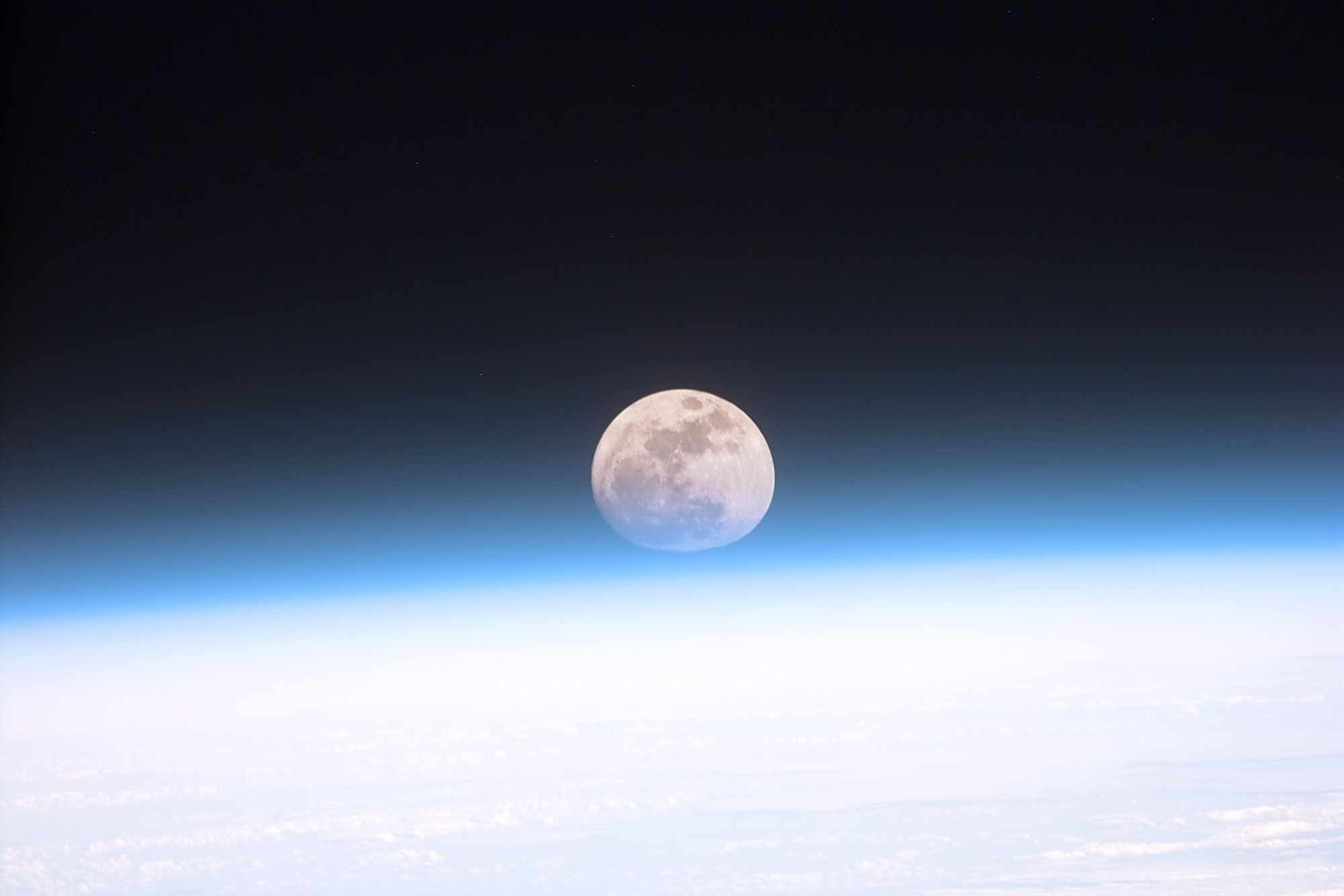 Full moon partially covered by the blue and white atmosphere