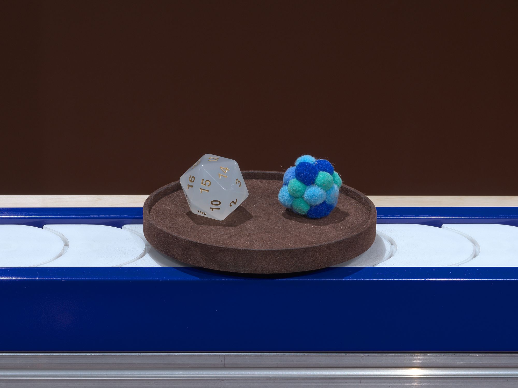 A dice and a small blue felt toy.