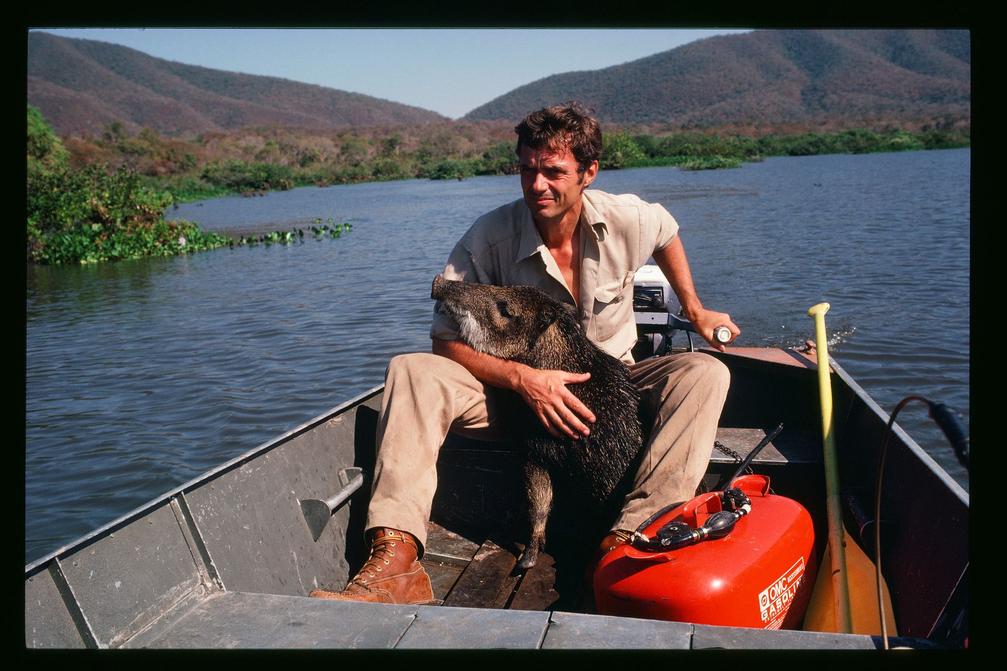 George Schaller holding a wild boar in a canoe.