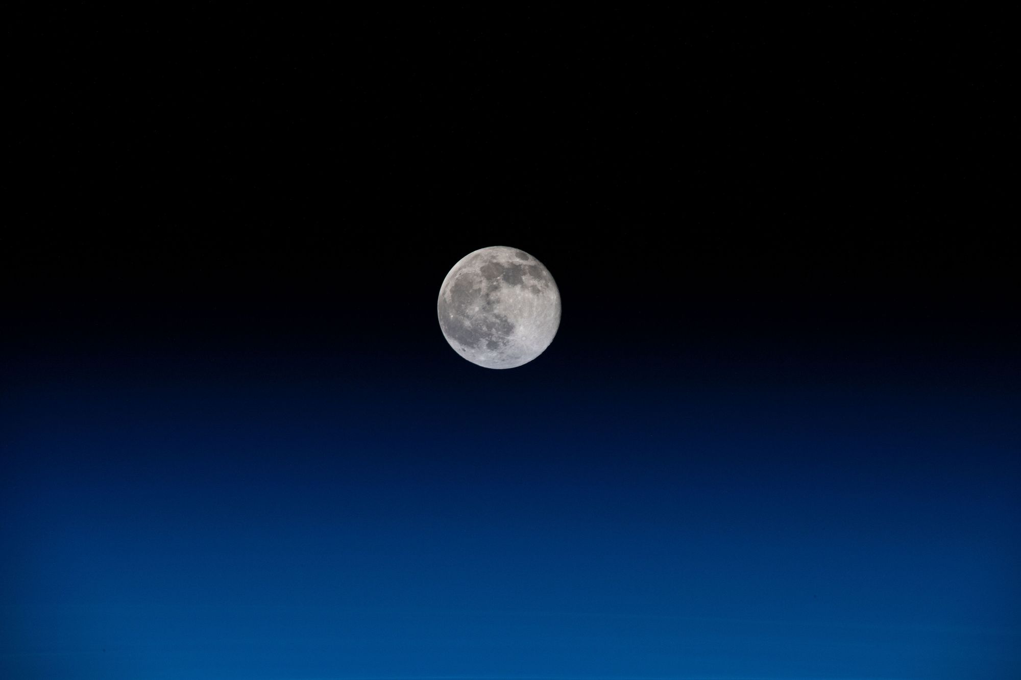 A Full Moon a darkening blue sky.