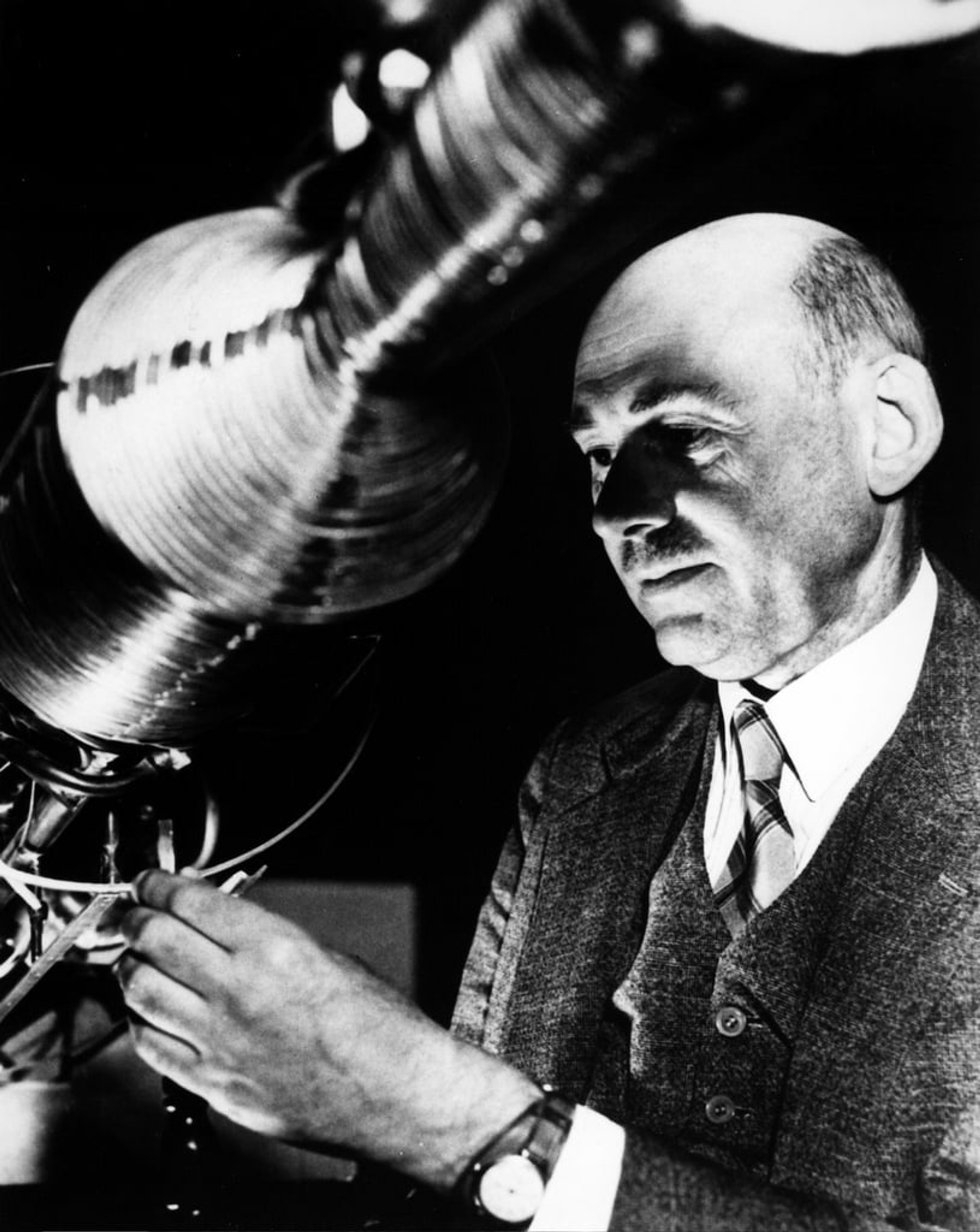 Black and white photo of Robert Goddard standing next to a rocket