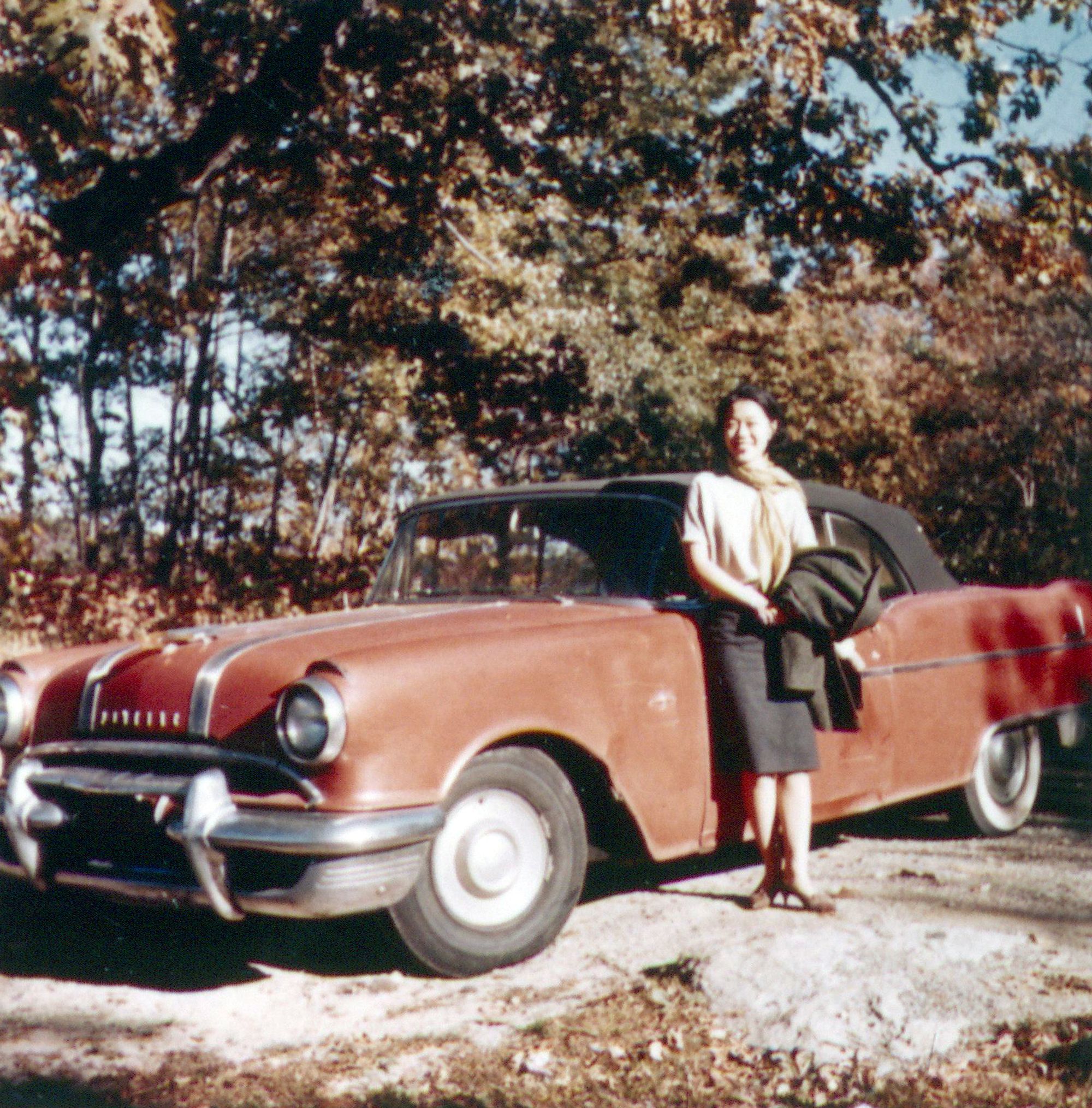 Woman standing in front of red car