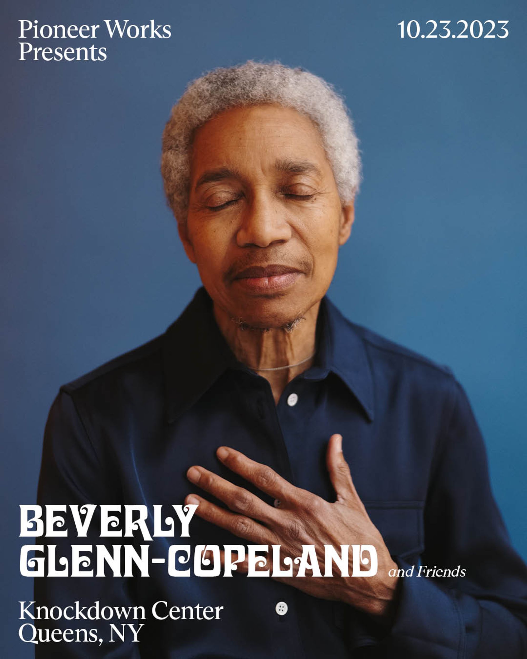 Beverly Glenn-Copeland with his left hand over his chest in front of a blue backdrop 