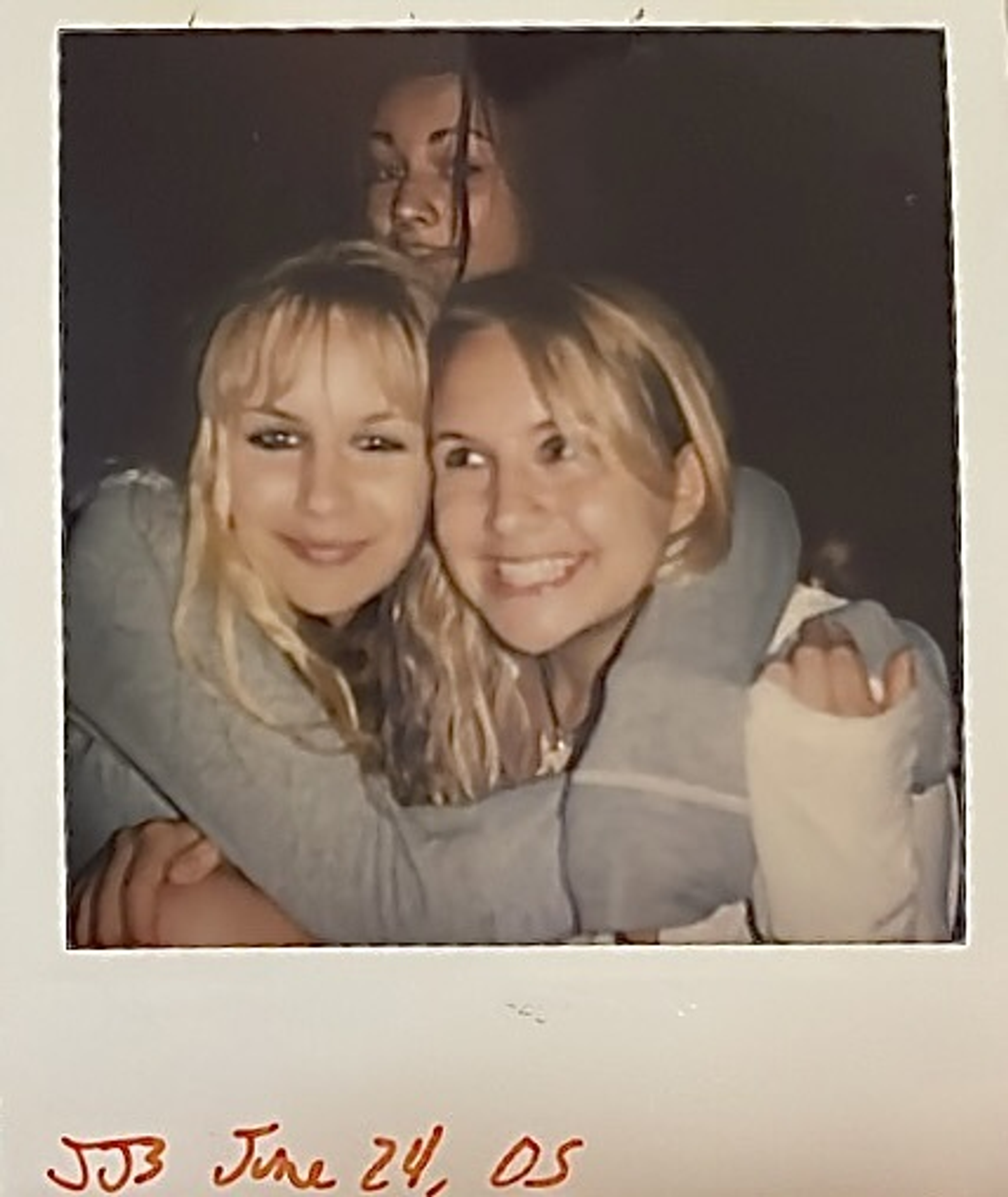 Two blonde girls embrace and smile.