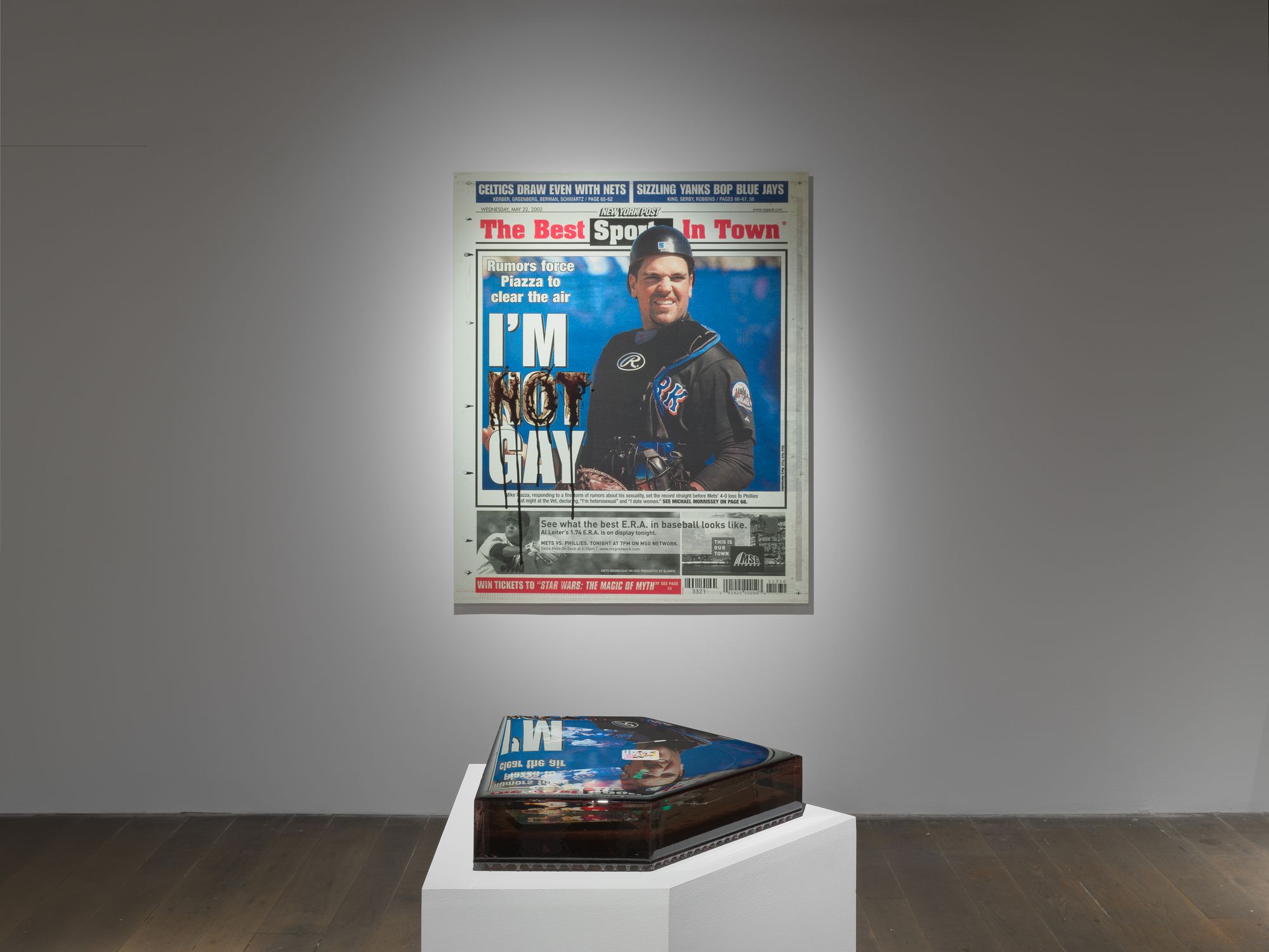 Newspaper front page is enlarged and hanging on the wall. The headline reads "I'm Not Gay".
