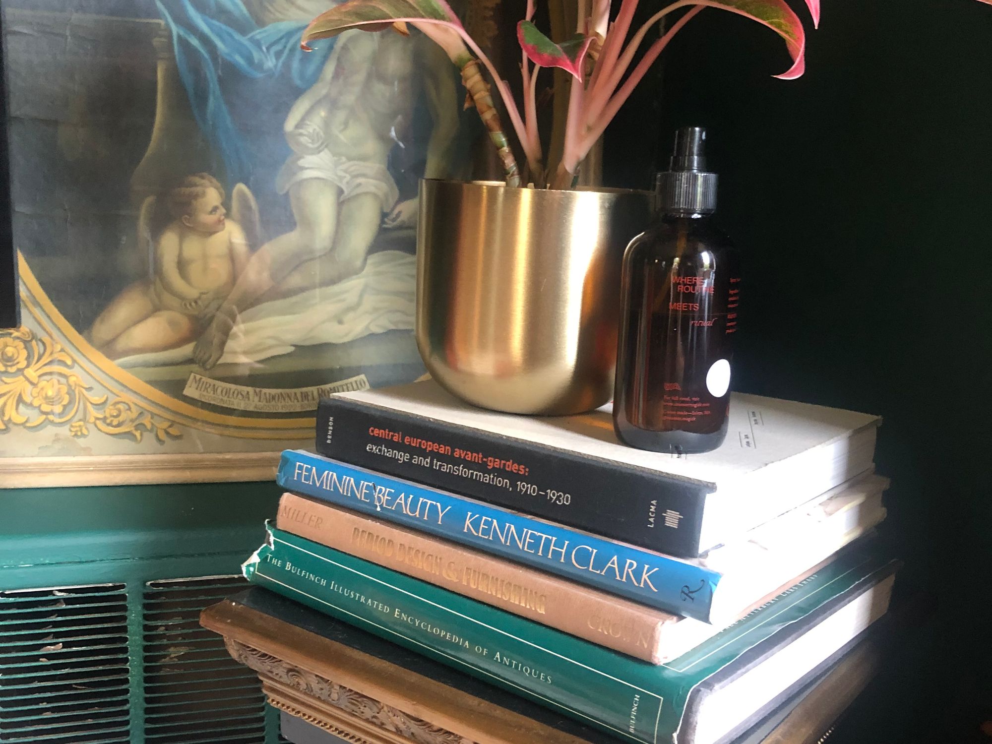 A photograph of a stack of books against the green wall of someone's living room.