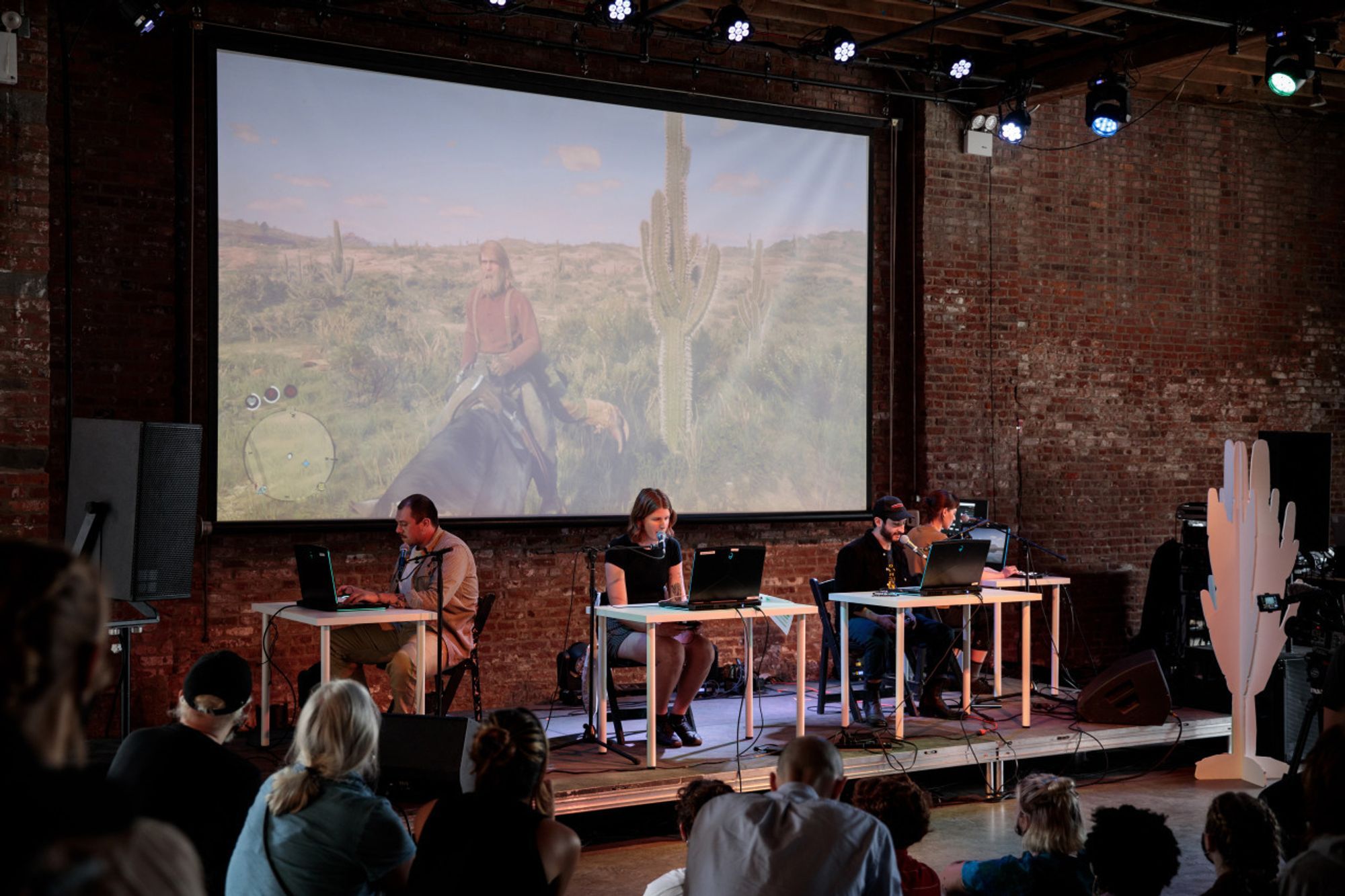 Three people sat at a table with microphones in front of a projected western scene