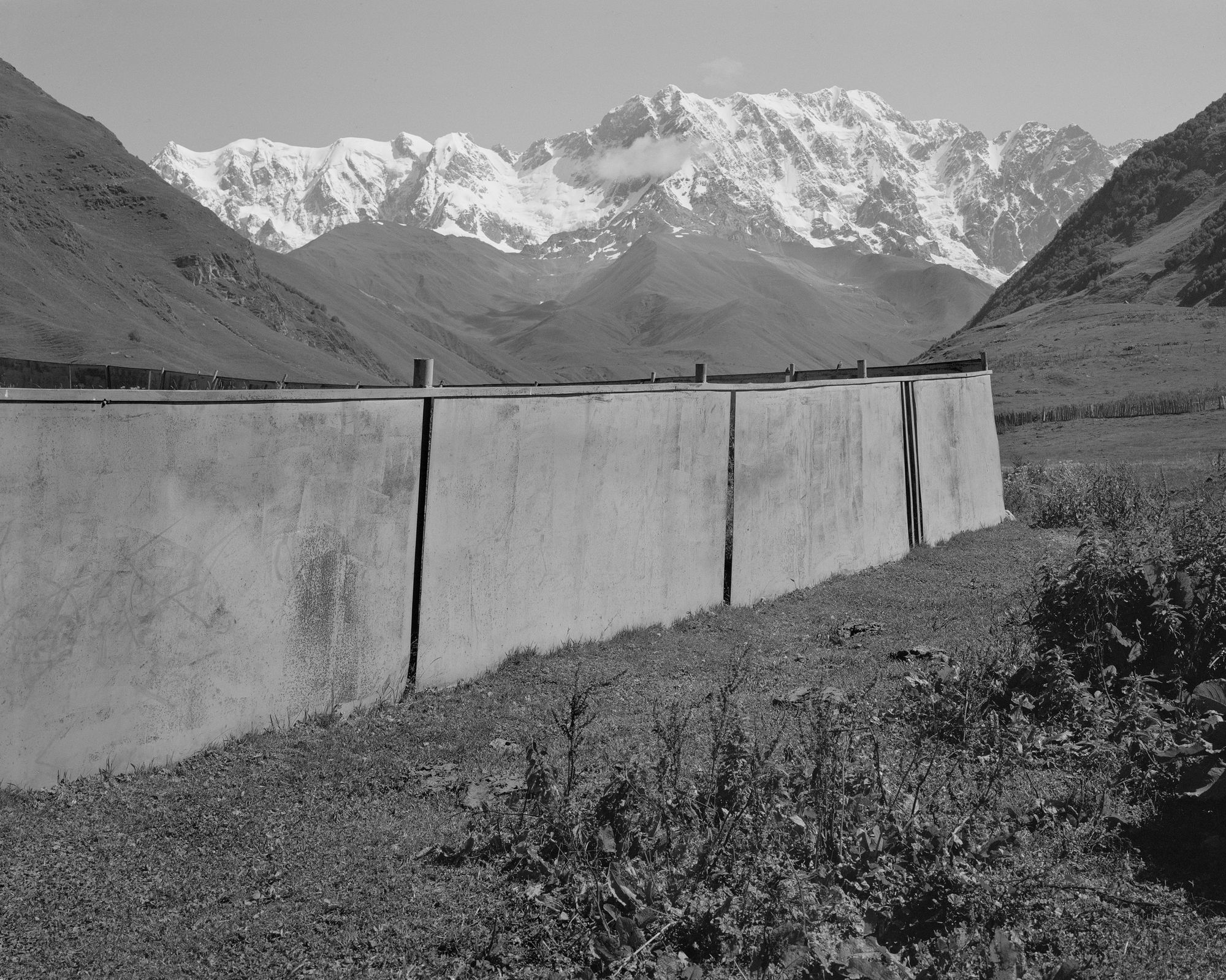 Black and white photo of a gate in a mountainous valley