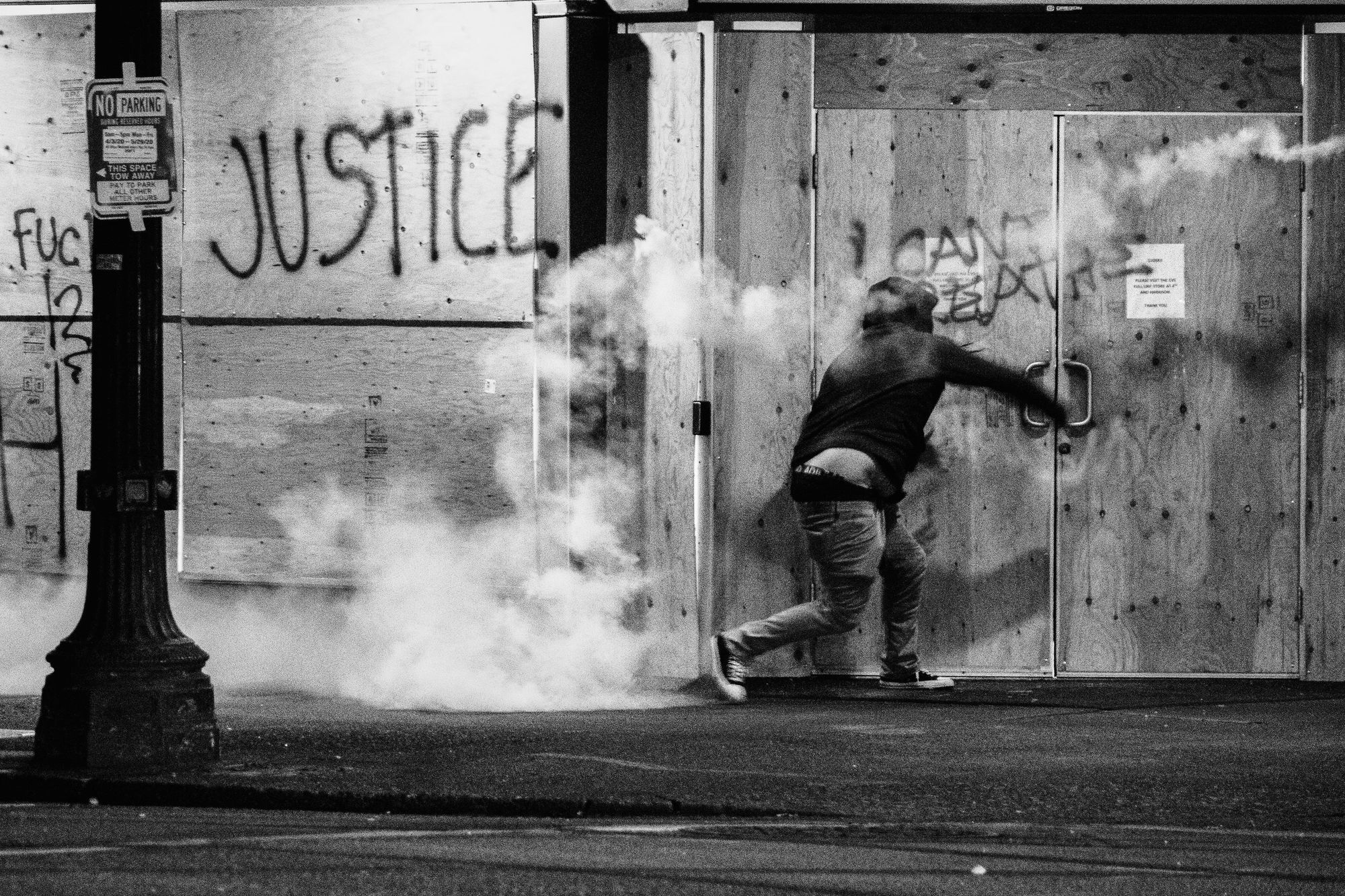 Male protester throwing a tear gas canister back towards the police