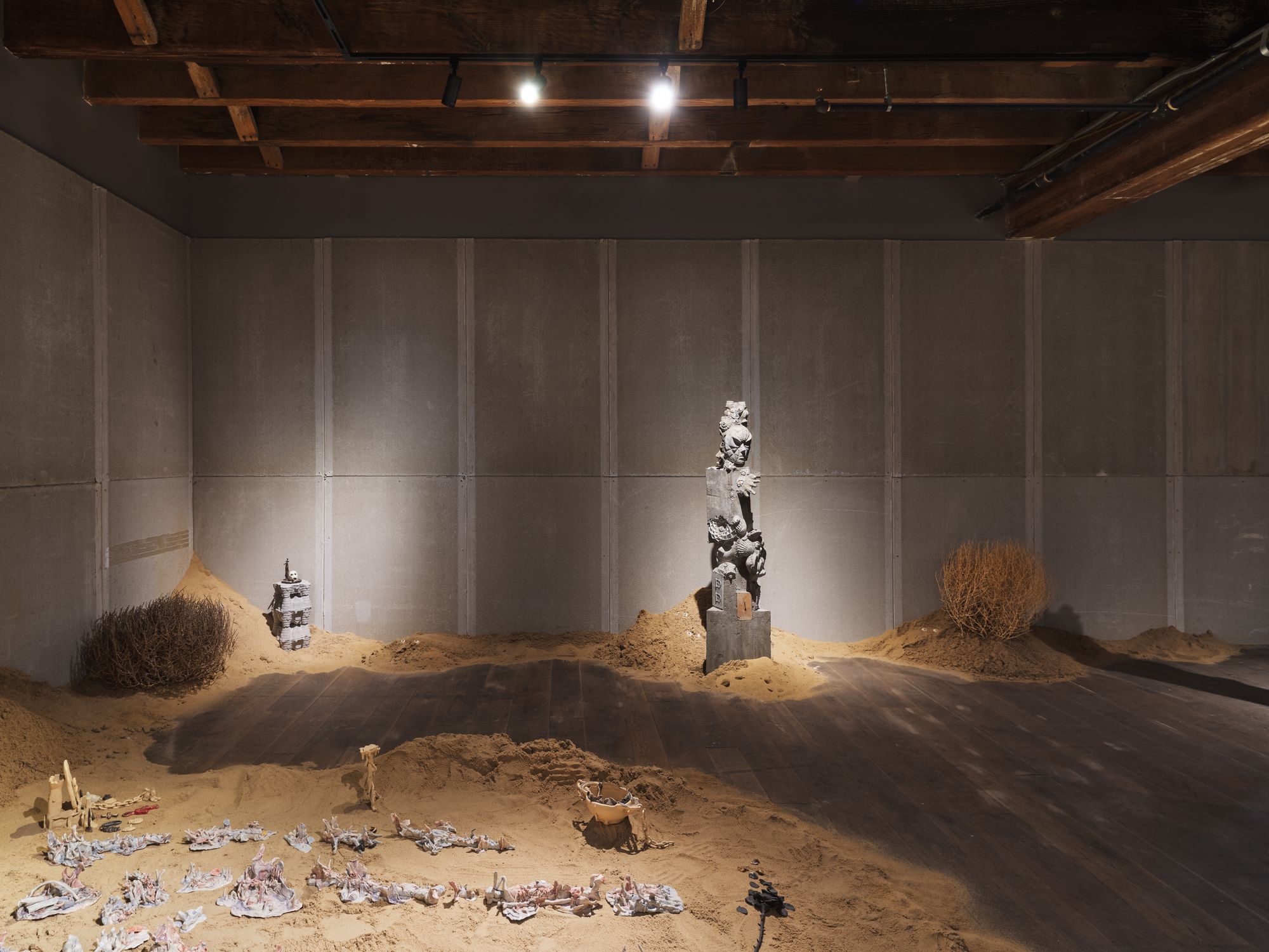 Concrete totems spotlit in a darkened gallery space.