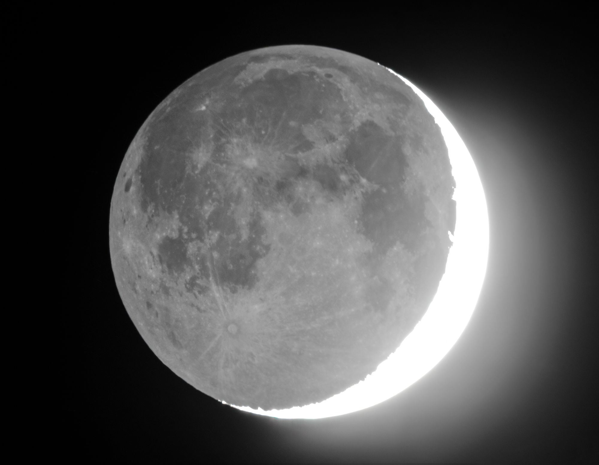 A close-up photograph of the moon with a crescent shape lit up on its side.