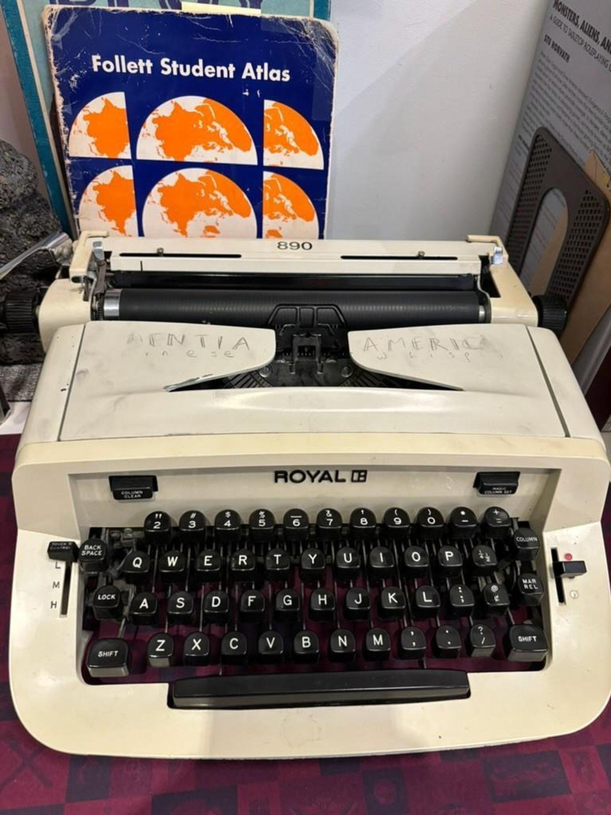 Image of a beige typewriter with a book propped behind it.