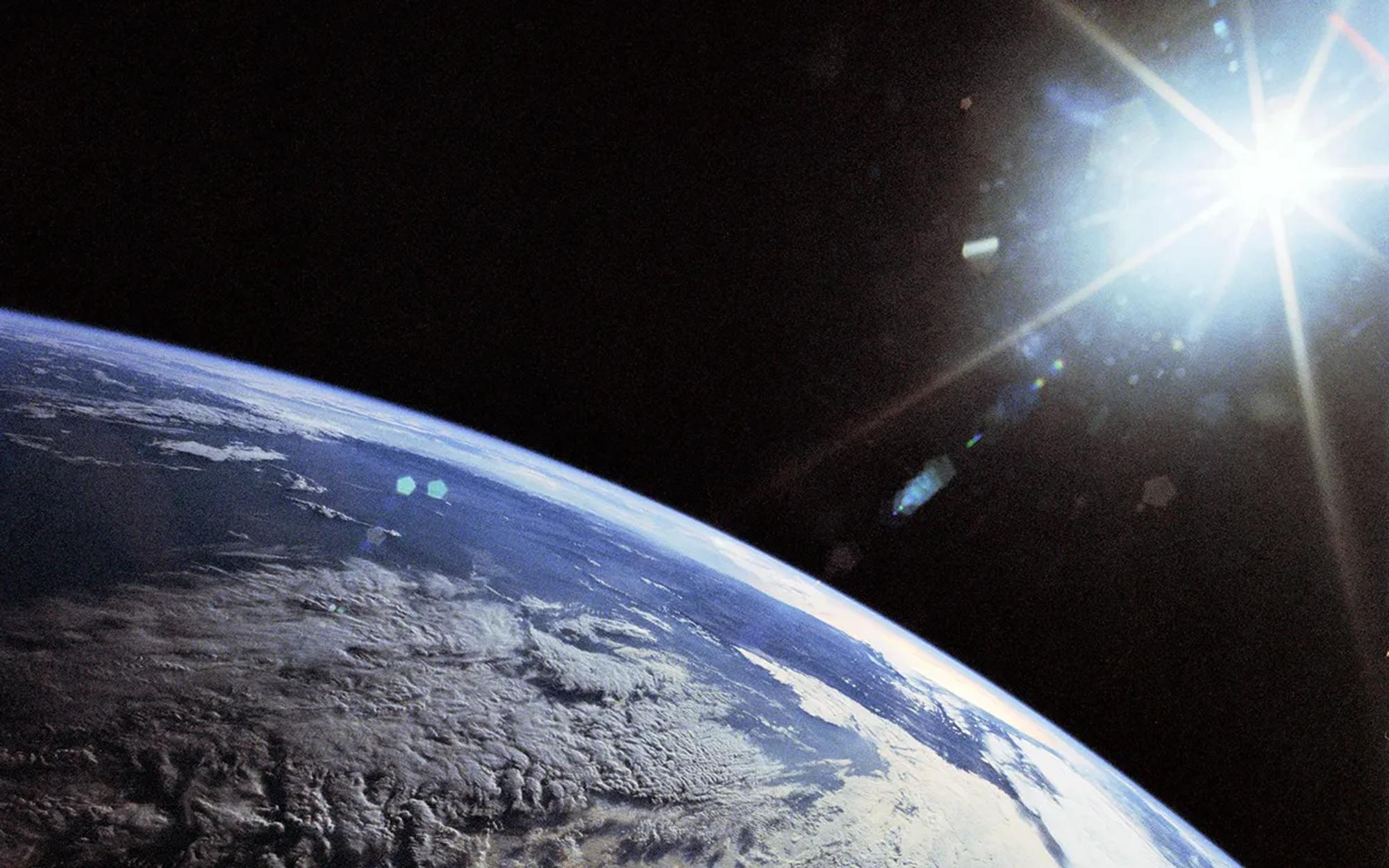 Quarter of planet Earth seen from space; shining light on the far right corner.