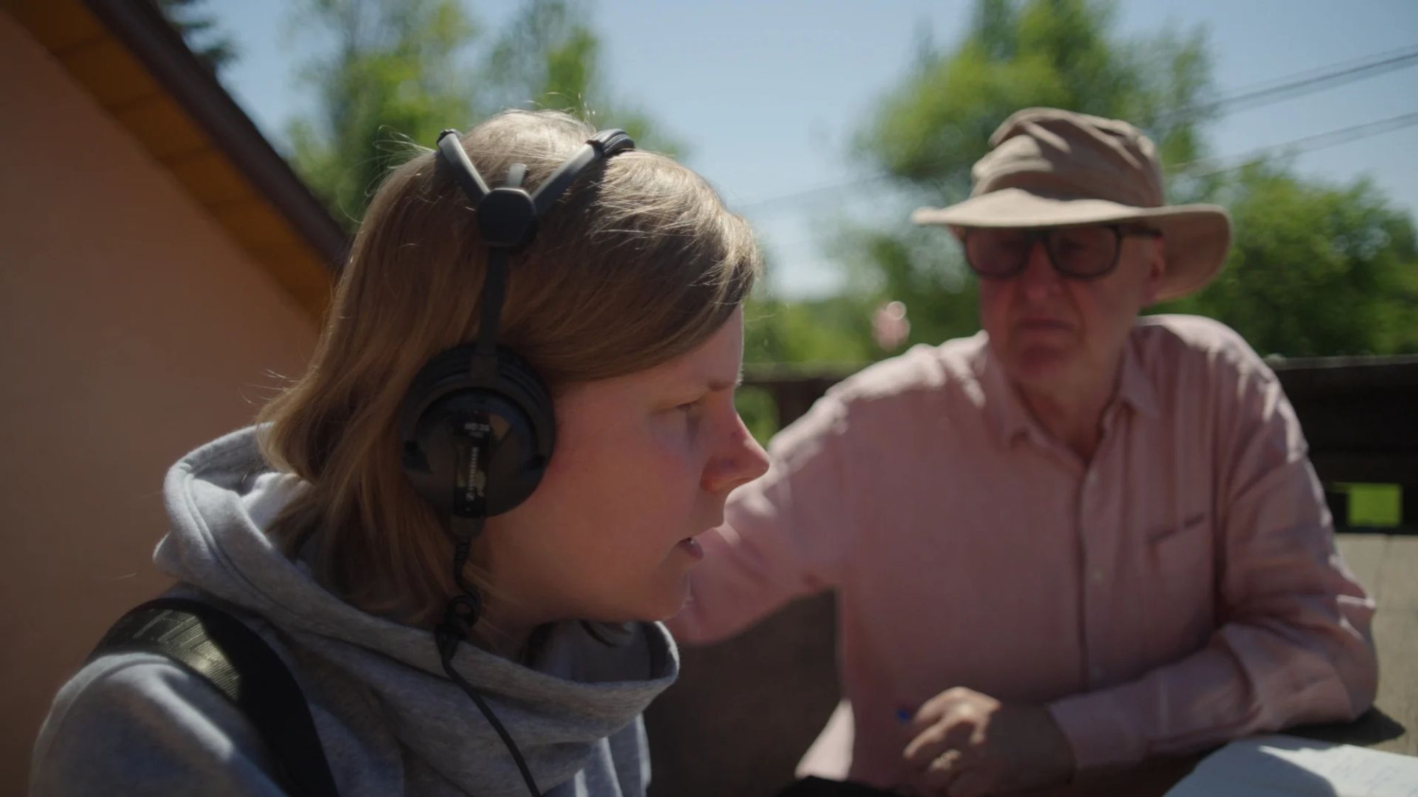 Izabela and Chris with headphones on recording sounds outdoors.