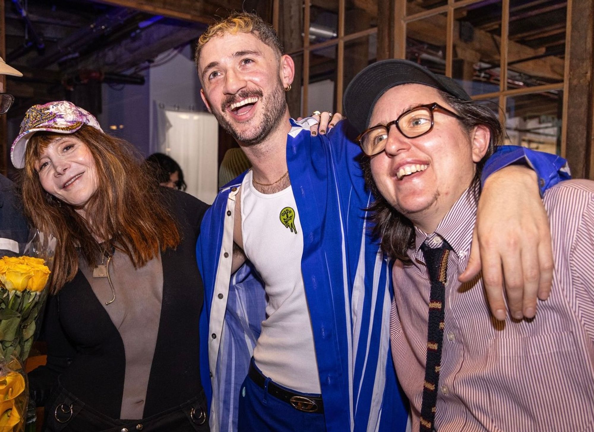Laura Albert holding flowers and hugging multiple other speakers at Pioneer Works.