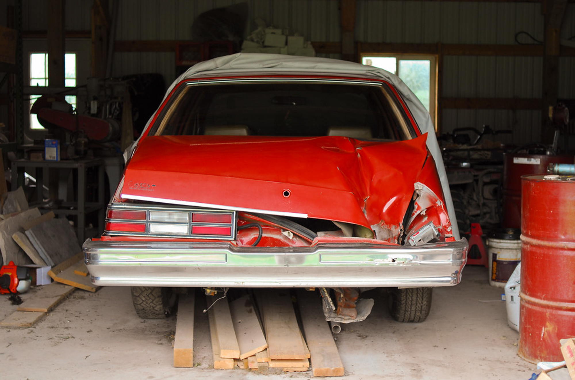 Red Malibu Chevy crushed in a garage