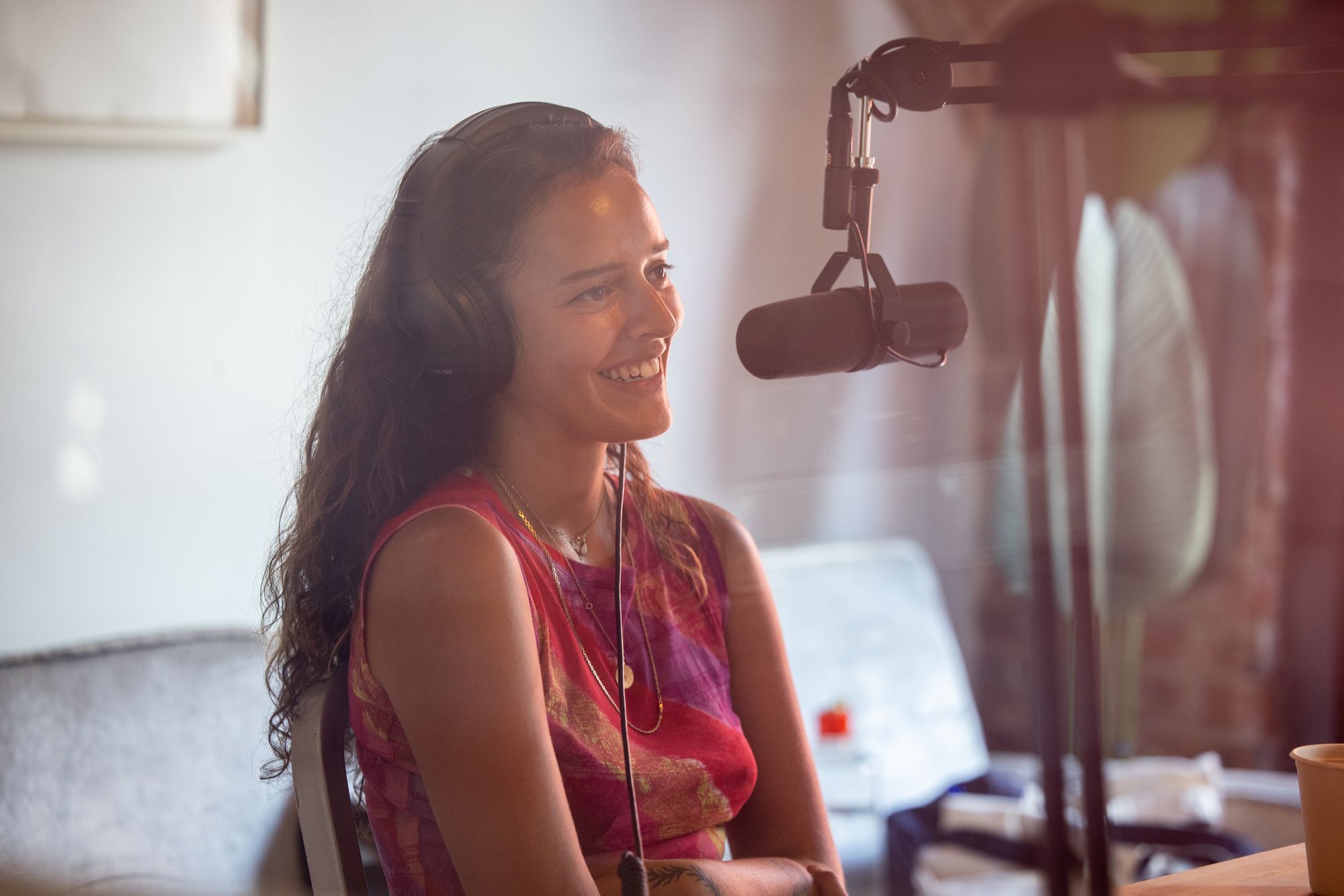 A person wearing headphones smiles into a microphone