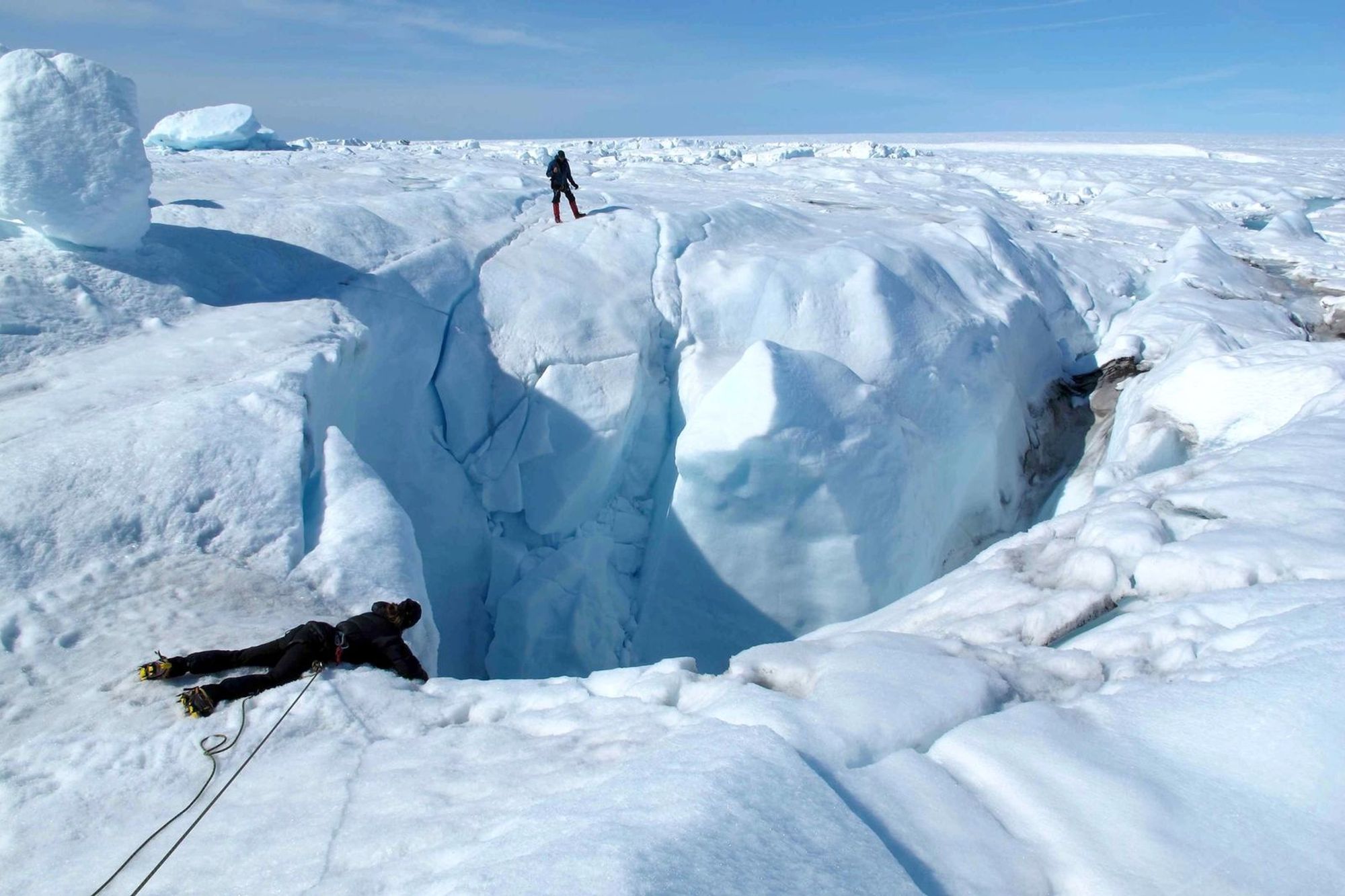 Photo of Marco Tedesco [far side of the “hole”] in Greenland on expedition described in his book The Hidden Life of Ice.