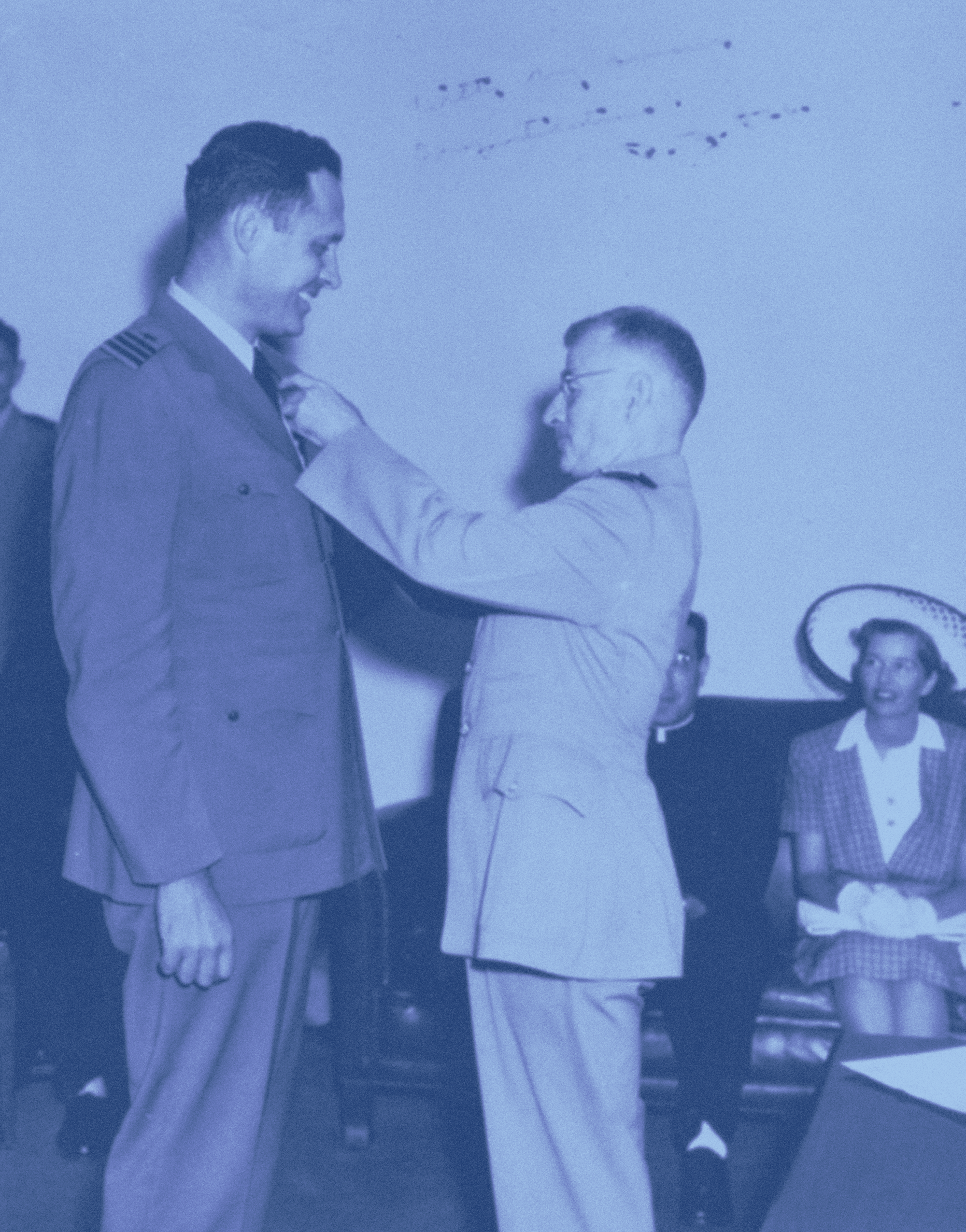 A man is presented with a commendation by a U.S. admiral, and smiles down on him.