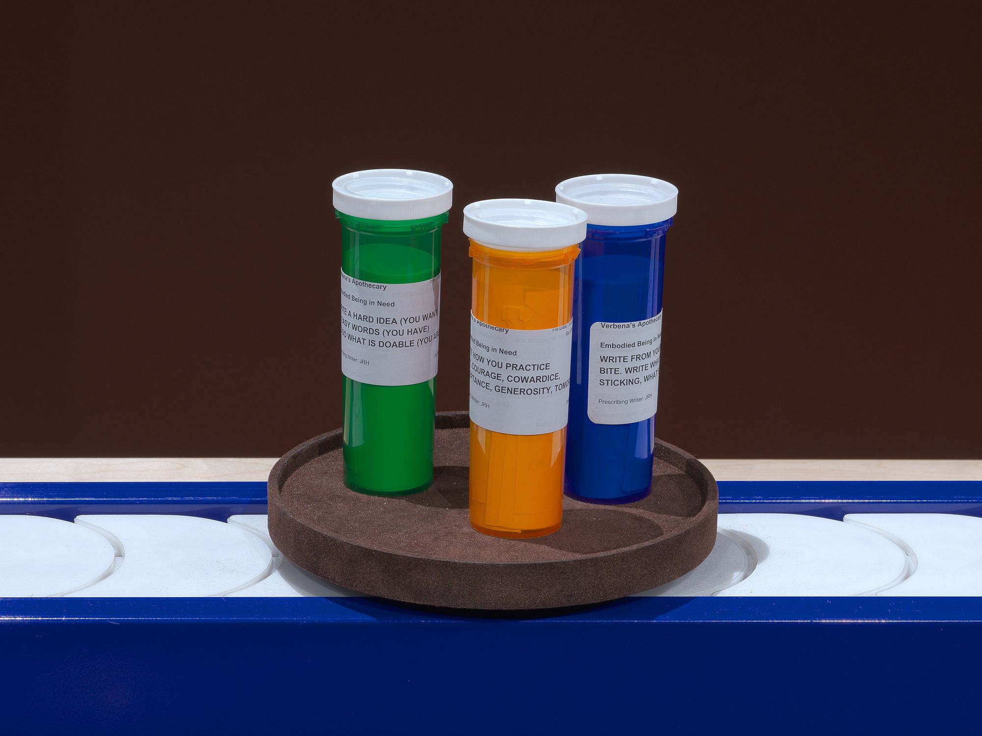 Three pill bottles floating on a blue conveyor belt