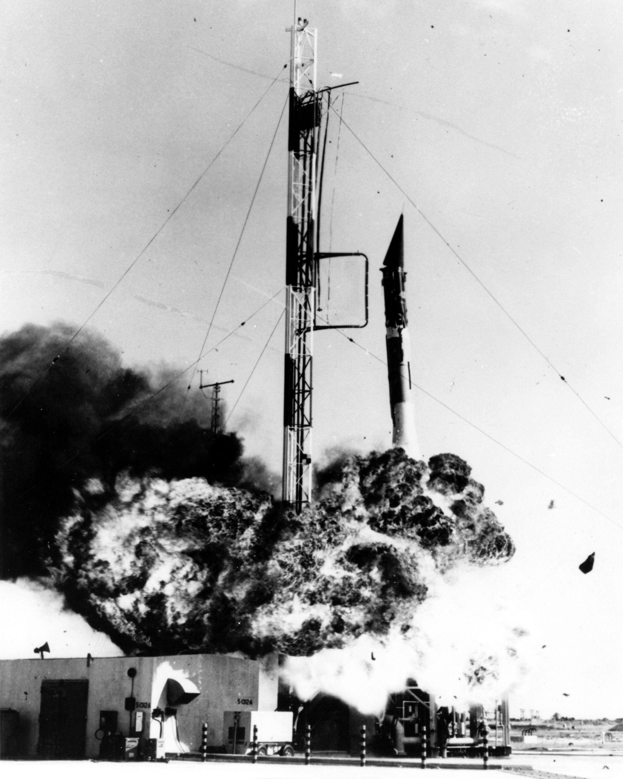 Black and white photograph of a rocket covered in smoke.