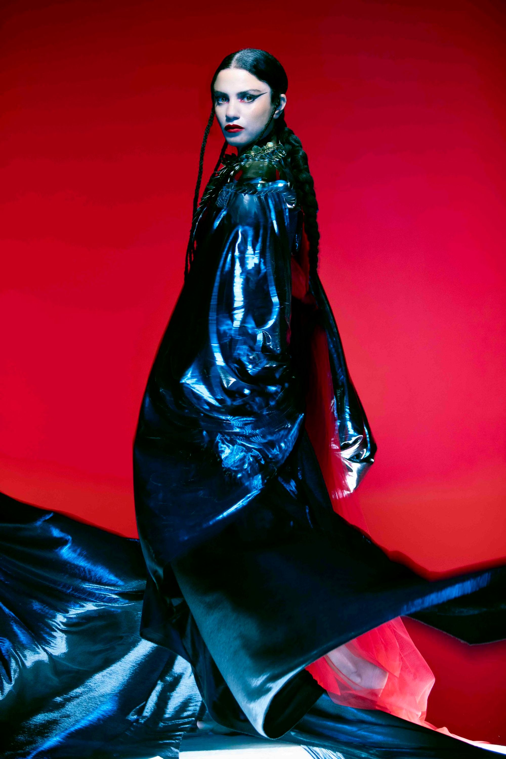 picture of emel with a black cape on and red background