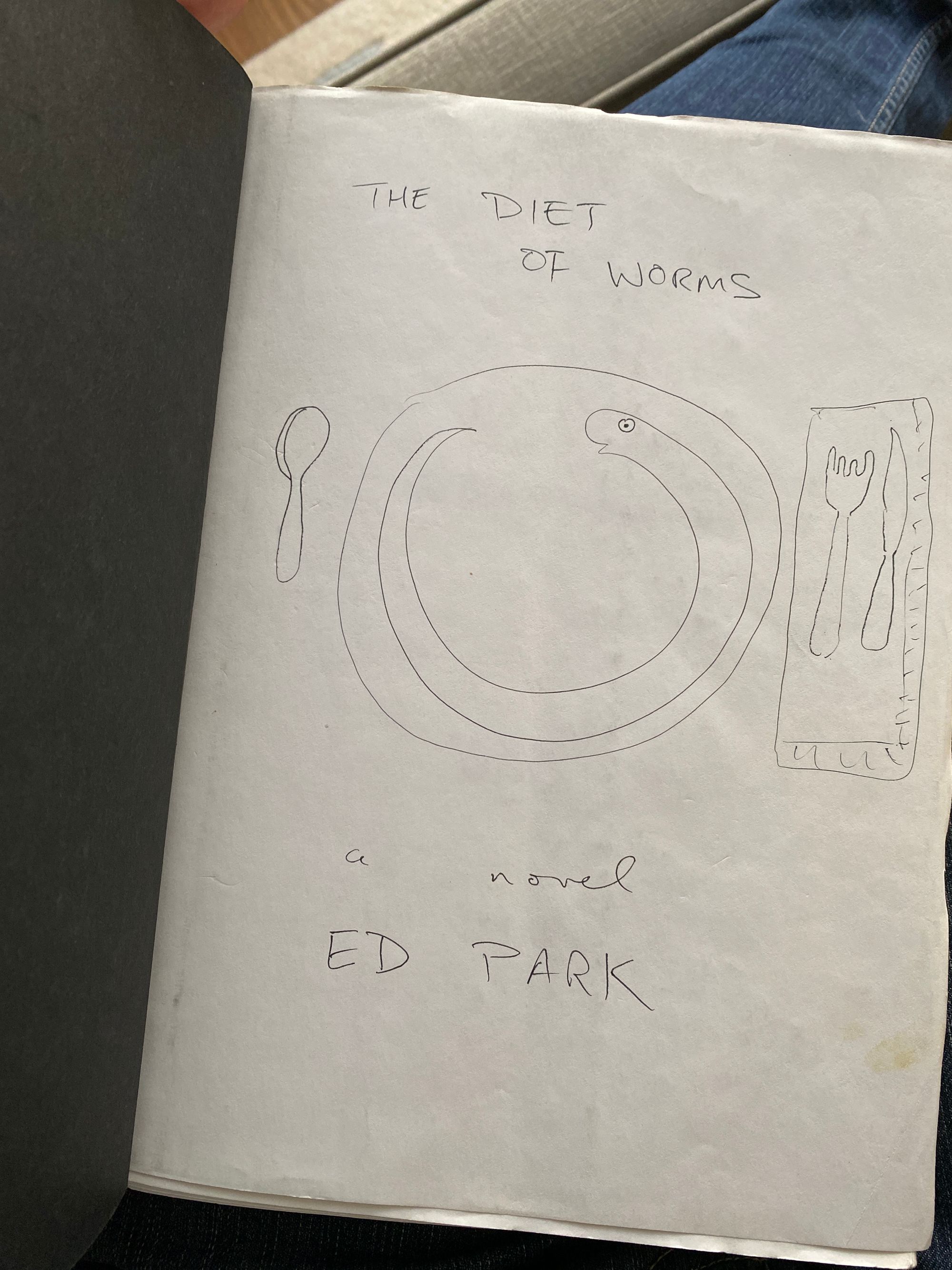 White piece of paper with blue scribbles that reads "The Diet of Worms by Ed Park."