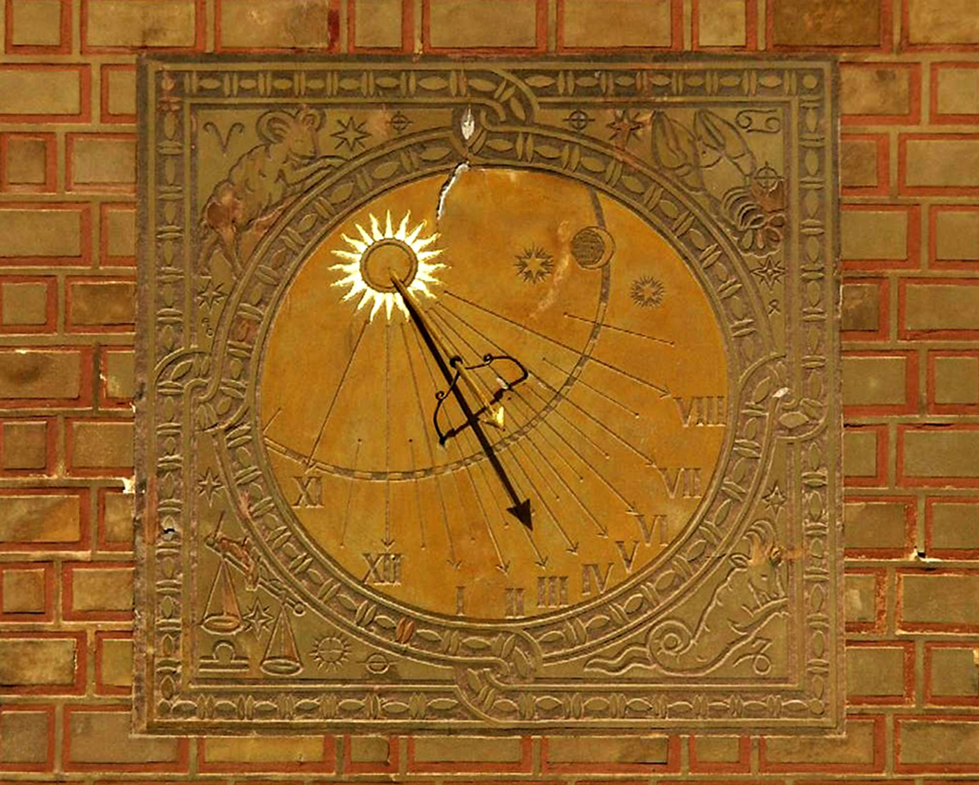 Sundial engraved into wall with gold and red brick