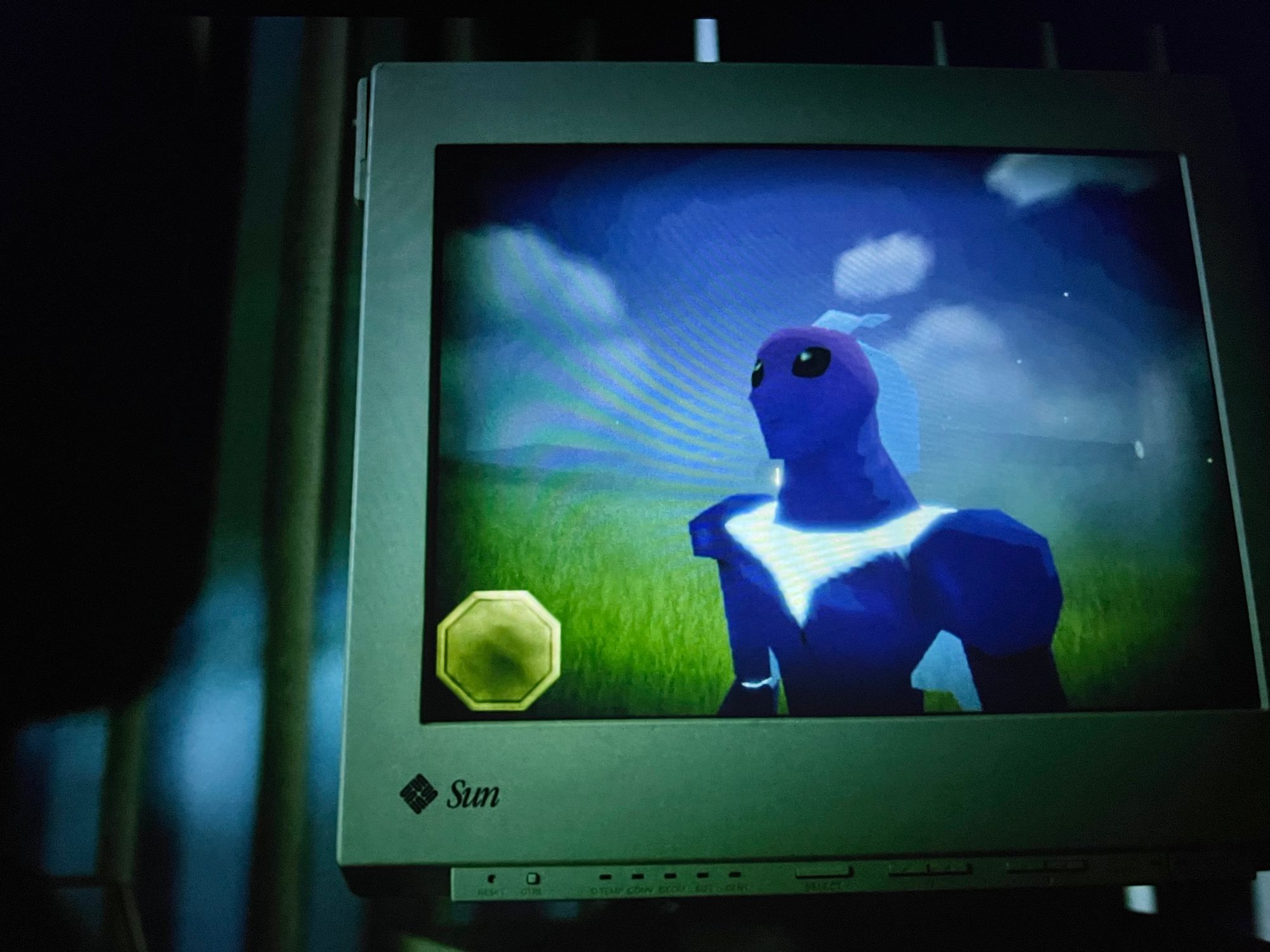 A figure with alien-looking eyes looks off into a distance on a 90s looking computer monitor. 