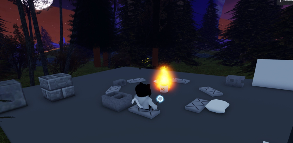 Screenshot of my avatar sitting at a fire in Roblox, holding a marshmallow, surrounded by the night sky with a big moon and dark trees.
