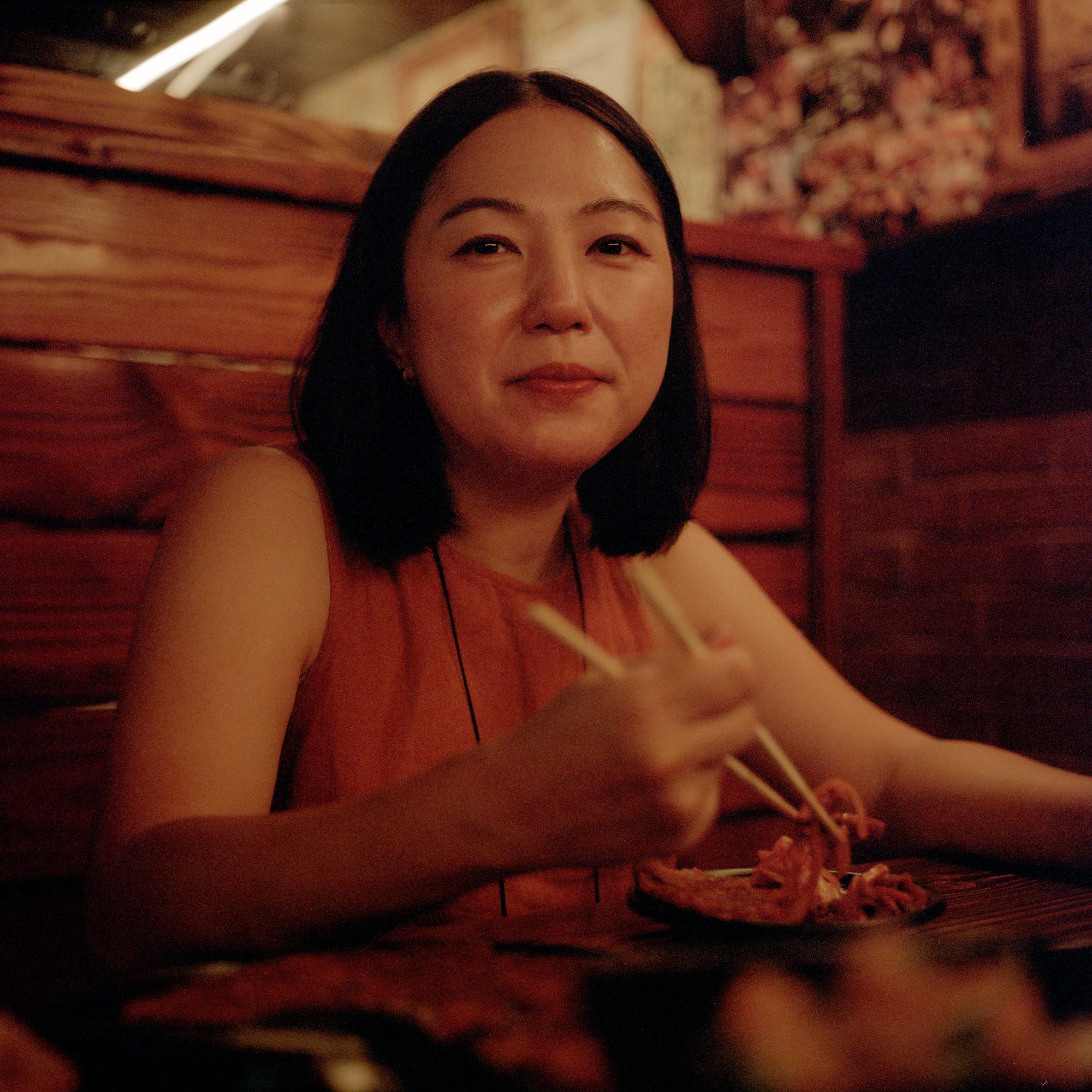 Maiko Kyogoku holds chopsticks in dimly lit restaurant.