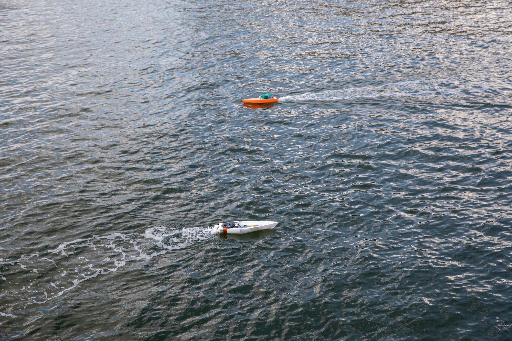 Two small boats pass each on the water as they move in opposite directions. 