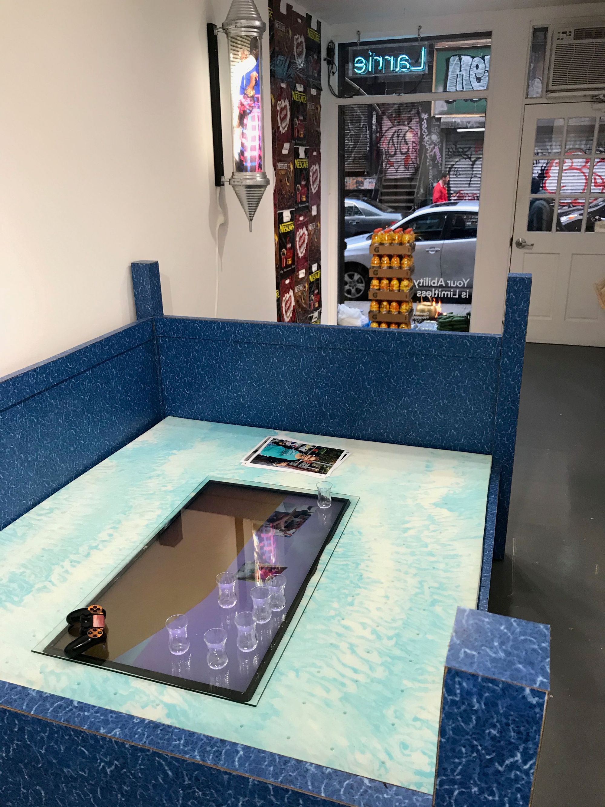 AURIC OASIS LOUNGE (2018), Mixed media installation with video game, wood, formica, gel mattress, controller, and digital print. 