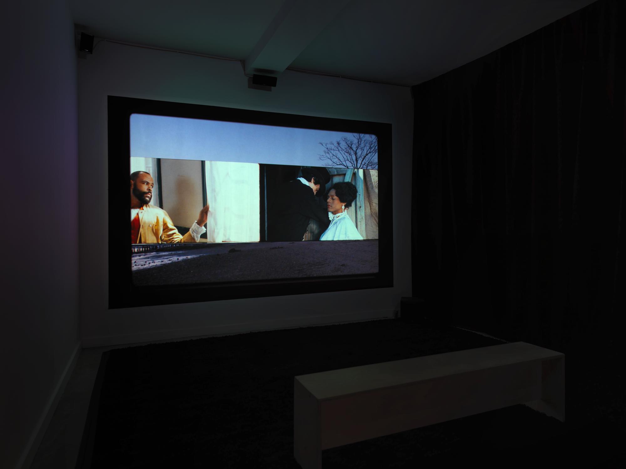 This installation view of Salacia depicts a scene with a man on the left and the portrayal of Mary Jones on the right. They are looking toward each other but it is unclear if they are in the same room.