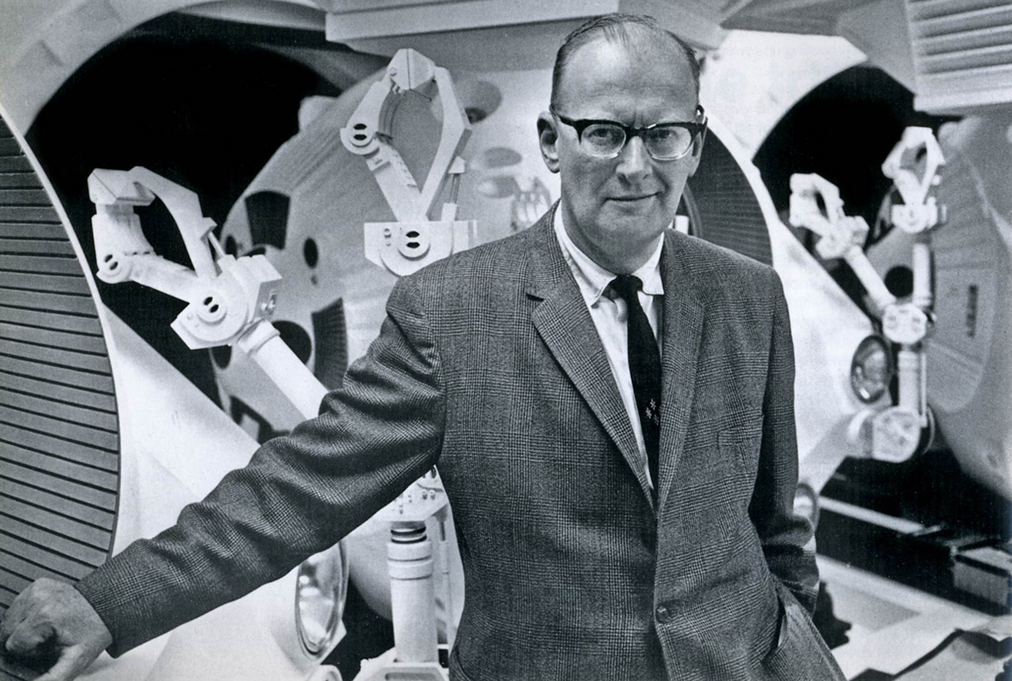 Black and white photograph Sir Arthur C. Clarke in front of space equipment 