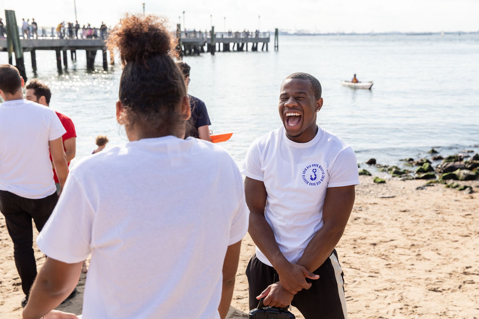 A young man laughs on a beach during the 2018 Red Hook Regatta boat race.