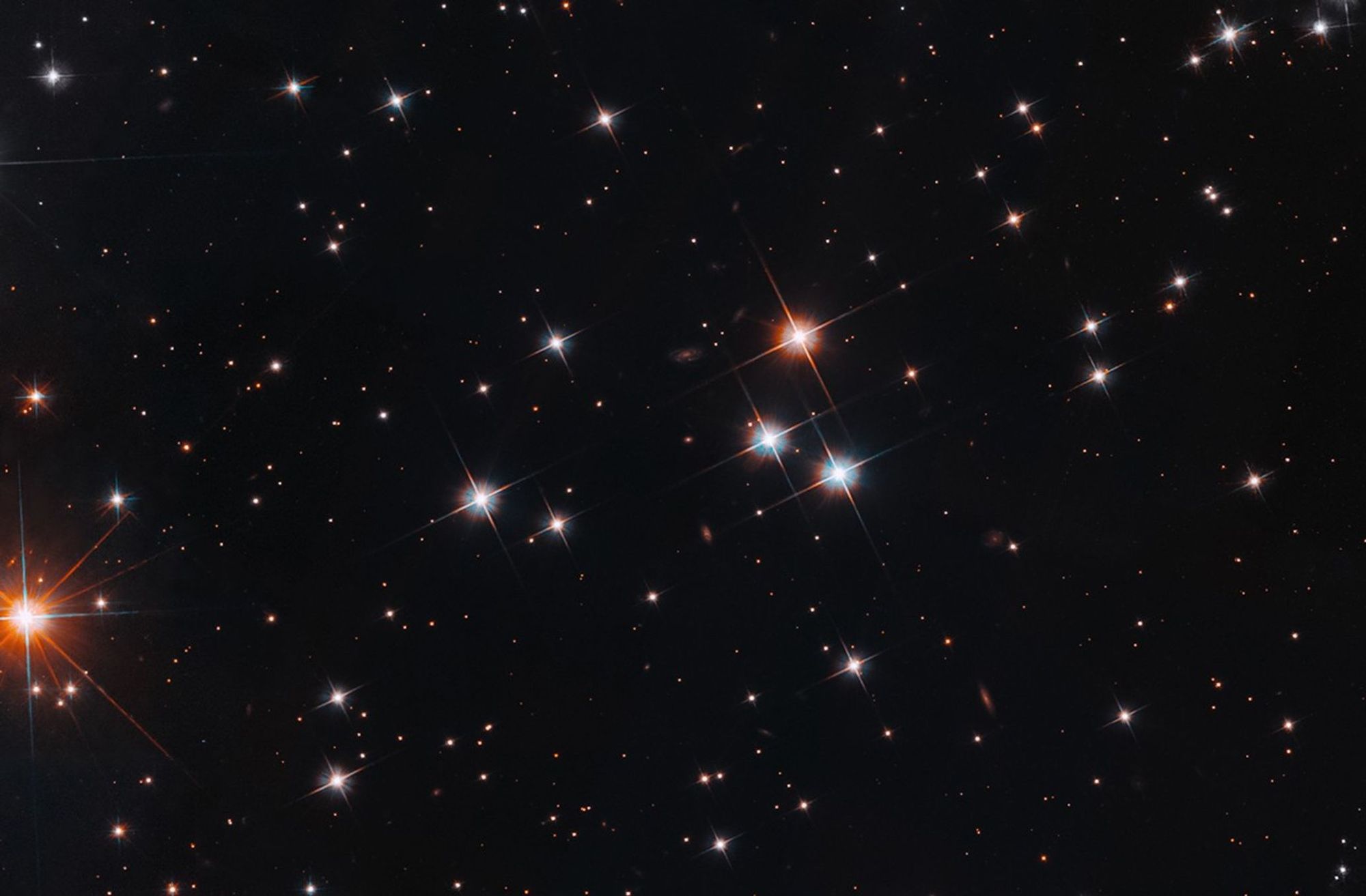 Dark space with bright cluster of stars scattered around.