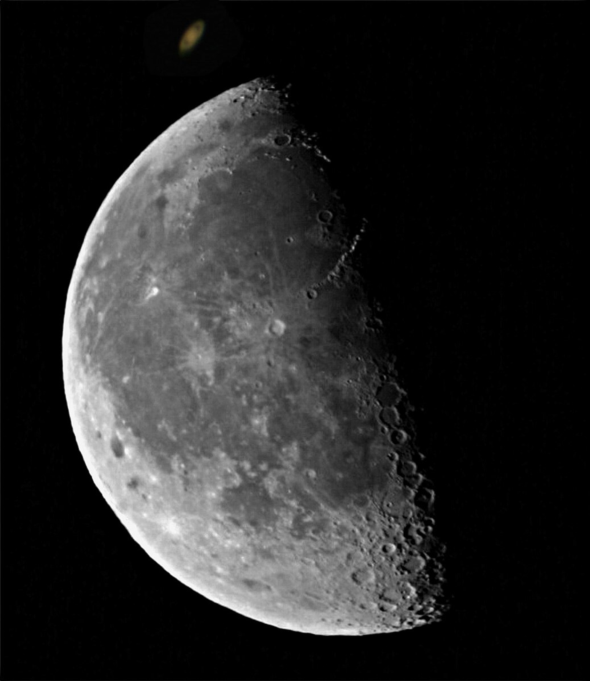 Photo of the moon in black space with saturn in the distance lighting ahead 