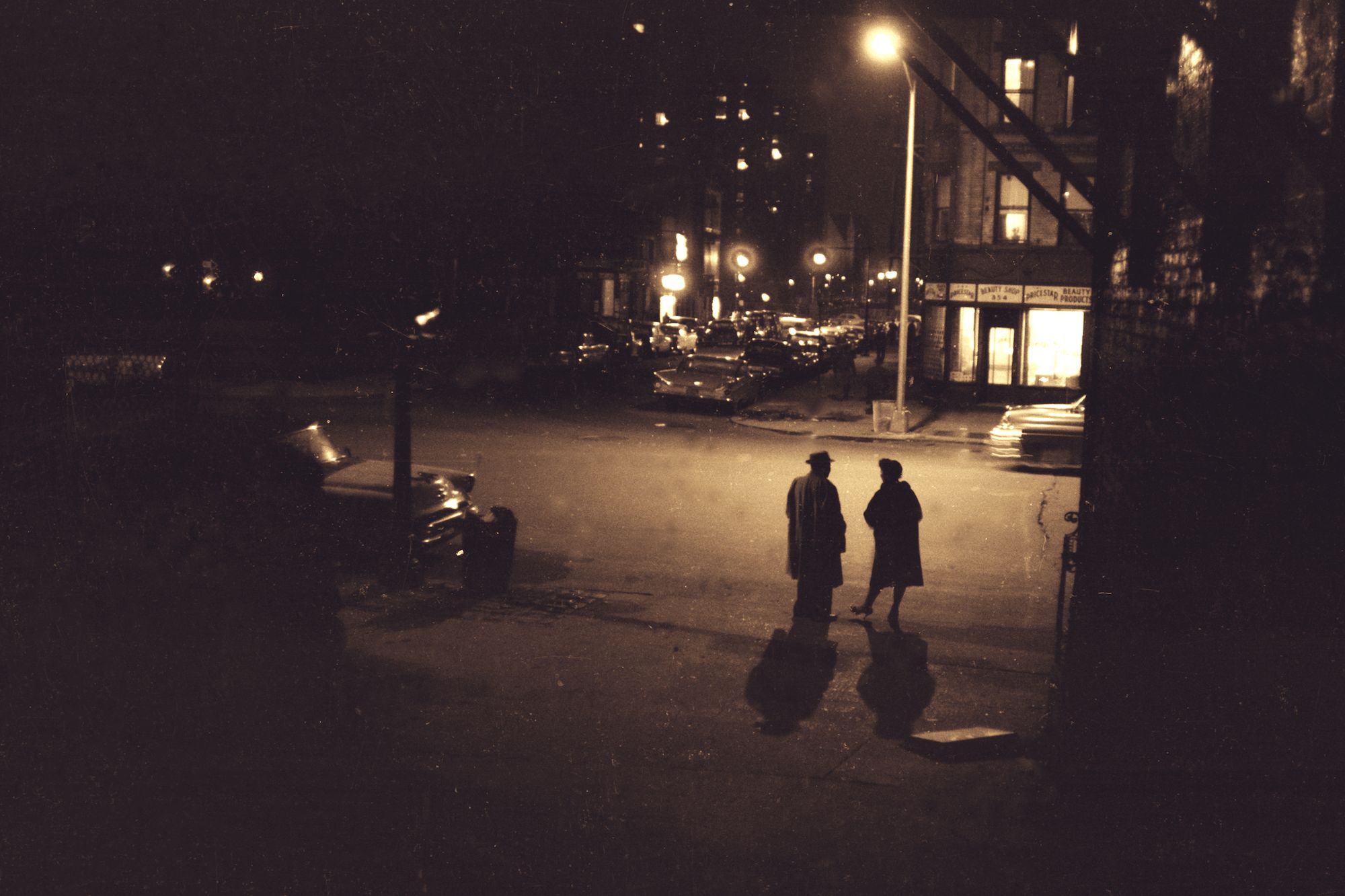 Black and white image of two figures on the street at night