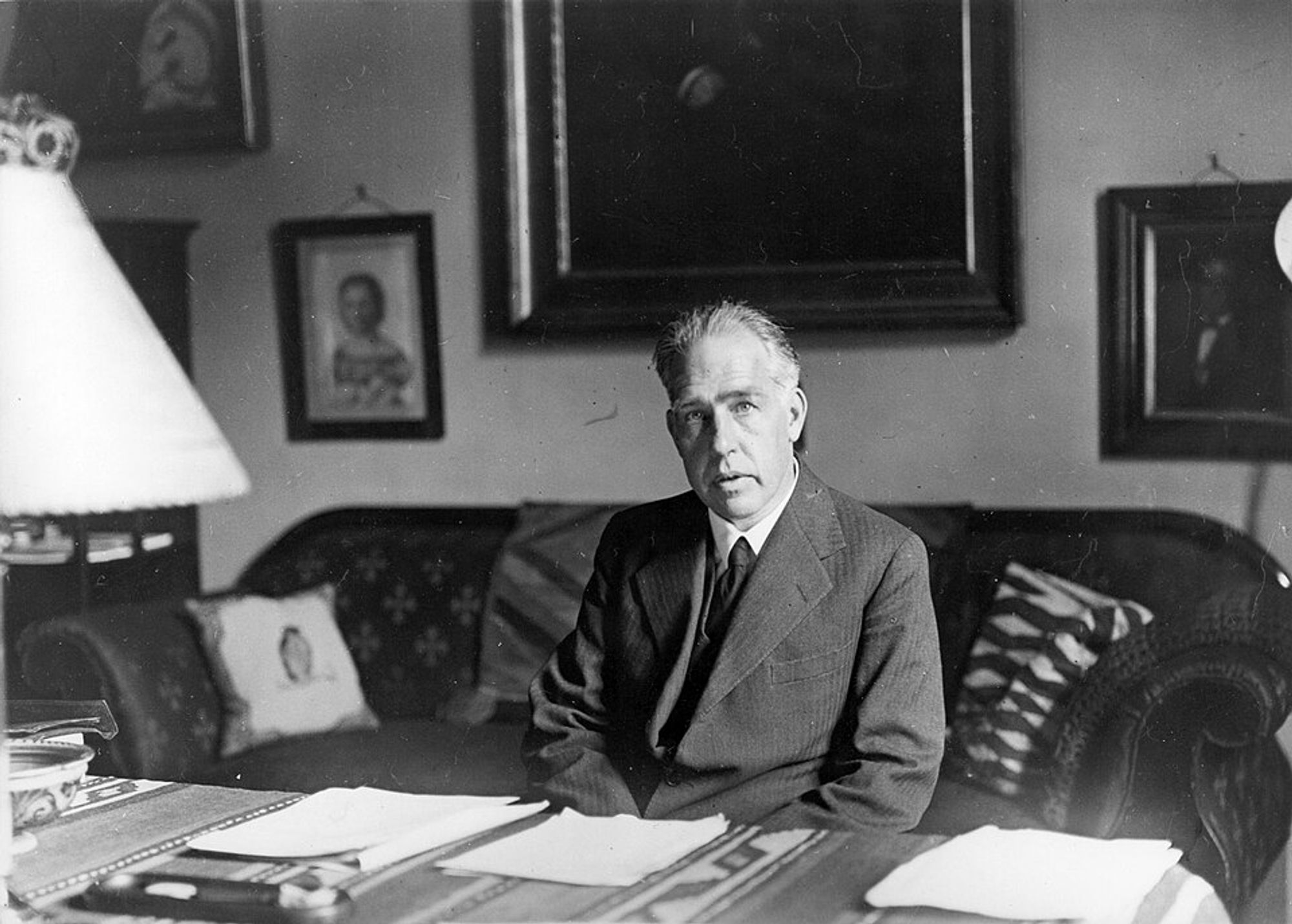 Black and white image of middle aged white man sitting at a desk.