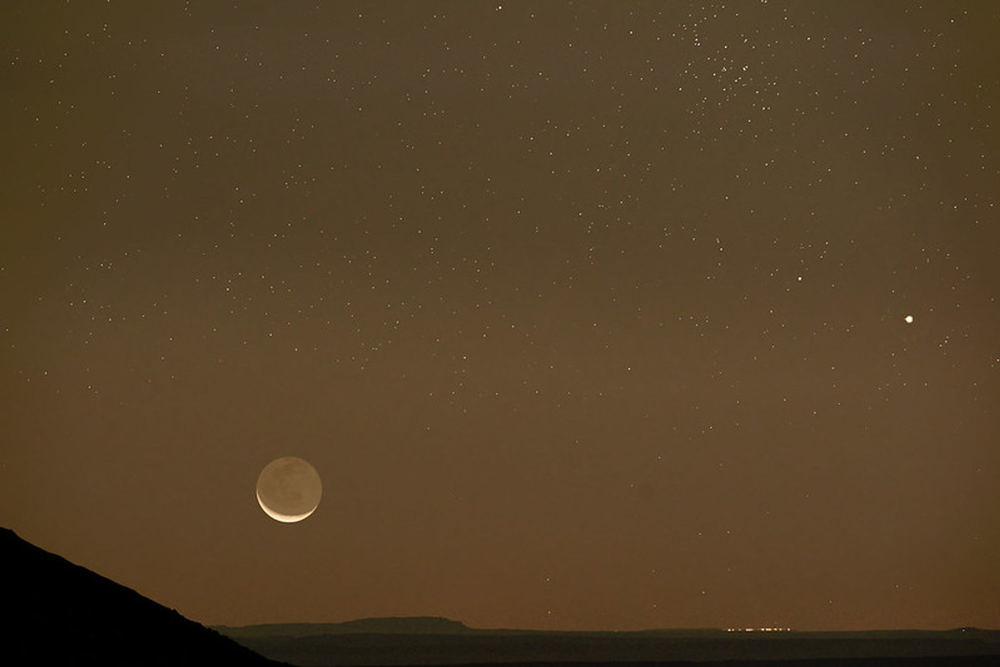 A yellowish-brown hazy sky with the moon and venus